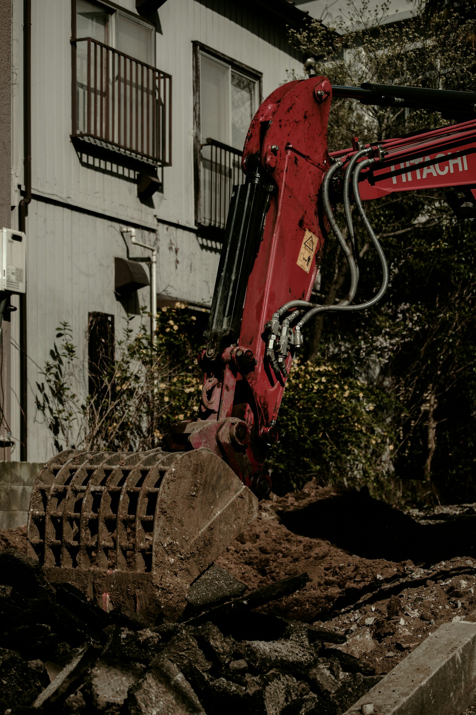 Máy xúc màu đỏ đang đào đất gần một tòa nhà