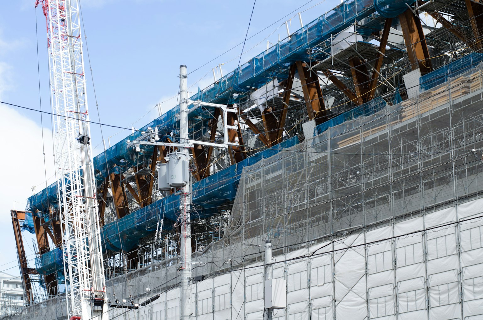 Site de construction d'un bâtiment avec échafaudage et grues visibles