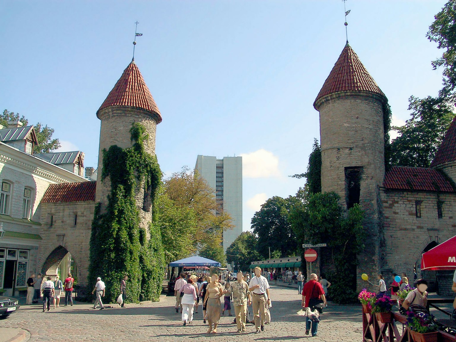 Historic towers with modern buildings in the background and people walking