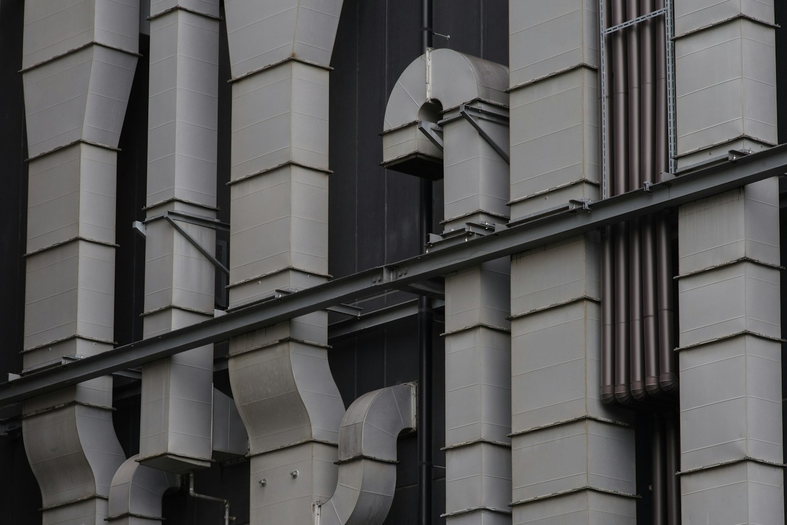 Pipes e strutture decorative su una facciata di edificio grigia