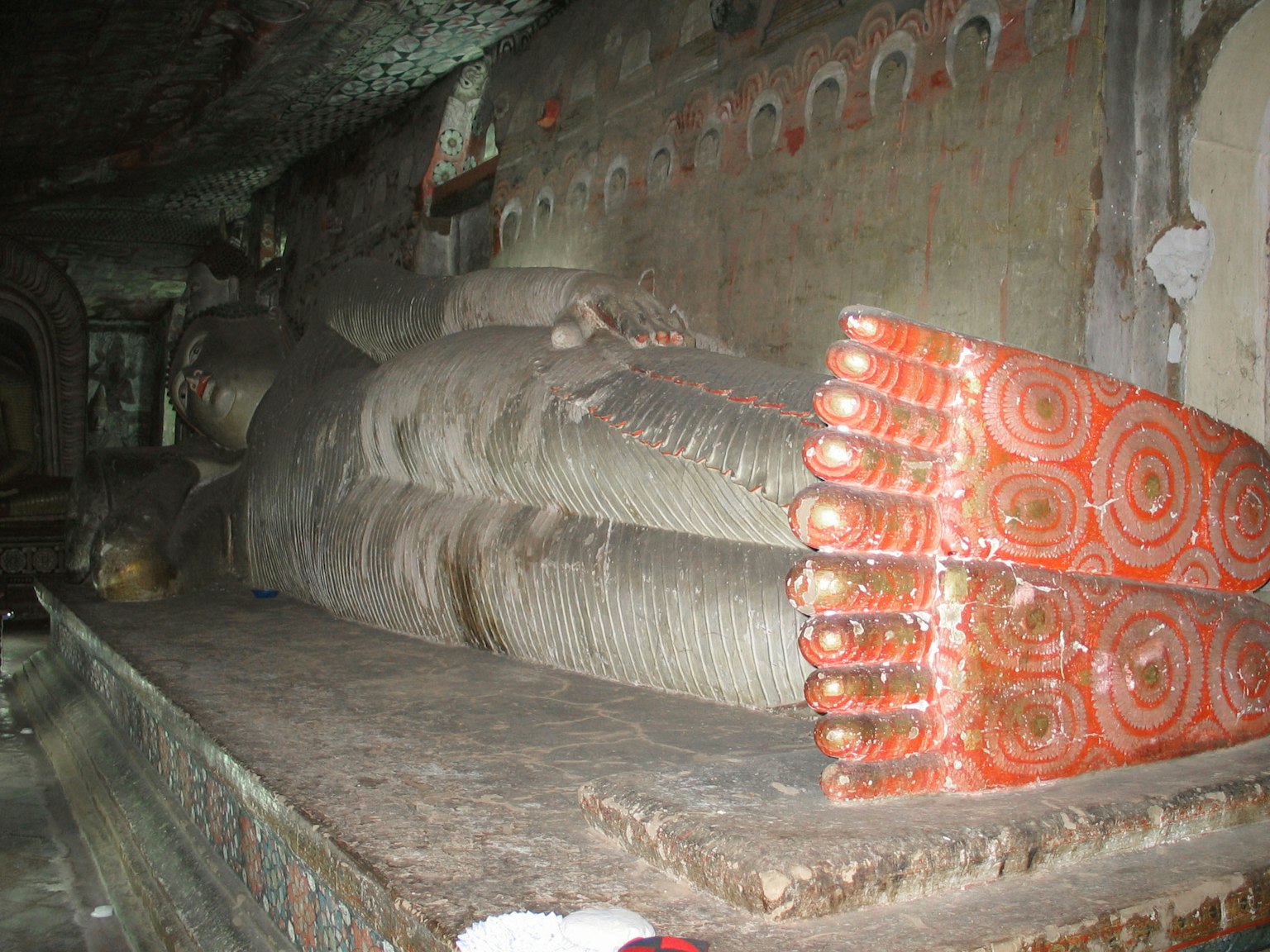 Large reclining Buddha statue inside a cave with colorful wall decorations