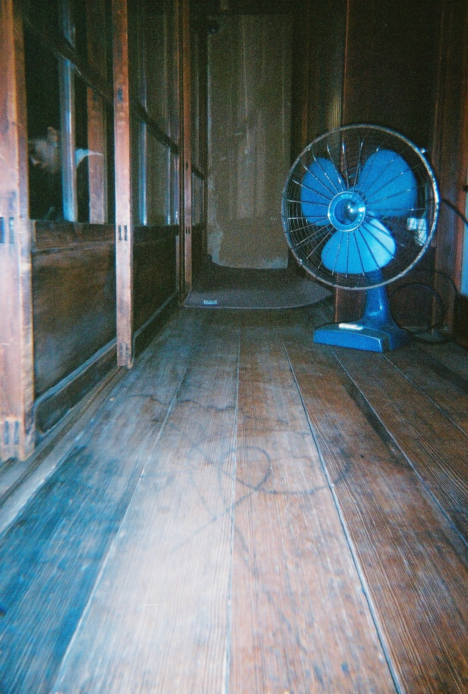 Innenraum mit einem alten Holzboden und einem blauen Ventilator