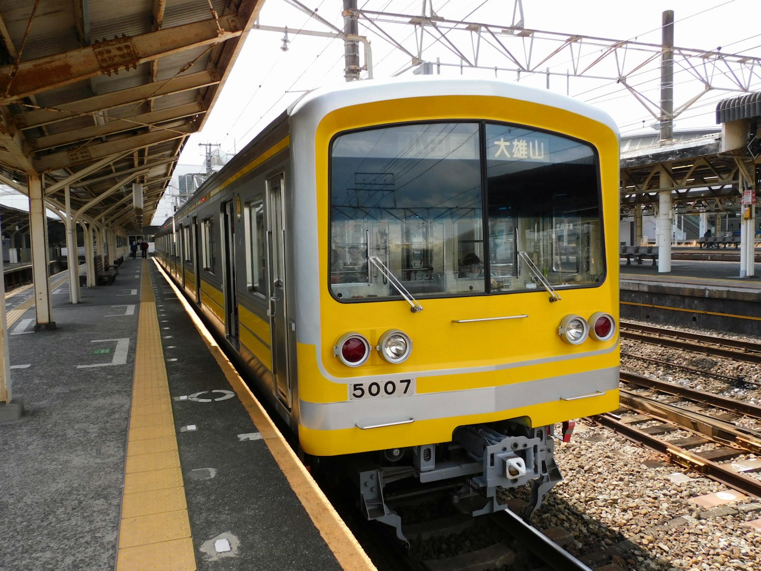 Kereta kuning diparkir di peron stasiun