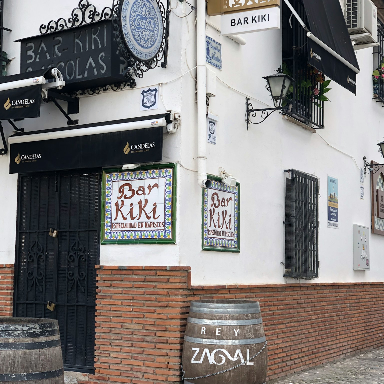 Exterior of Bar Kiki featuring white walls and wooden barrels