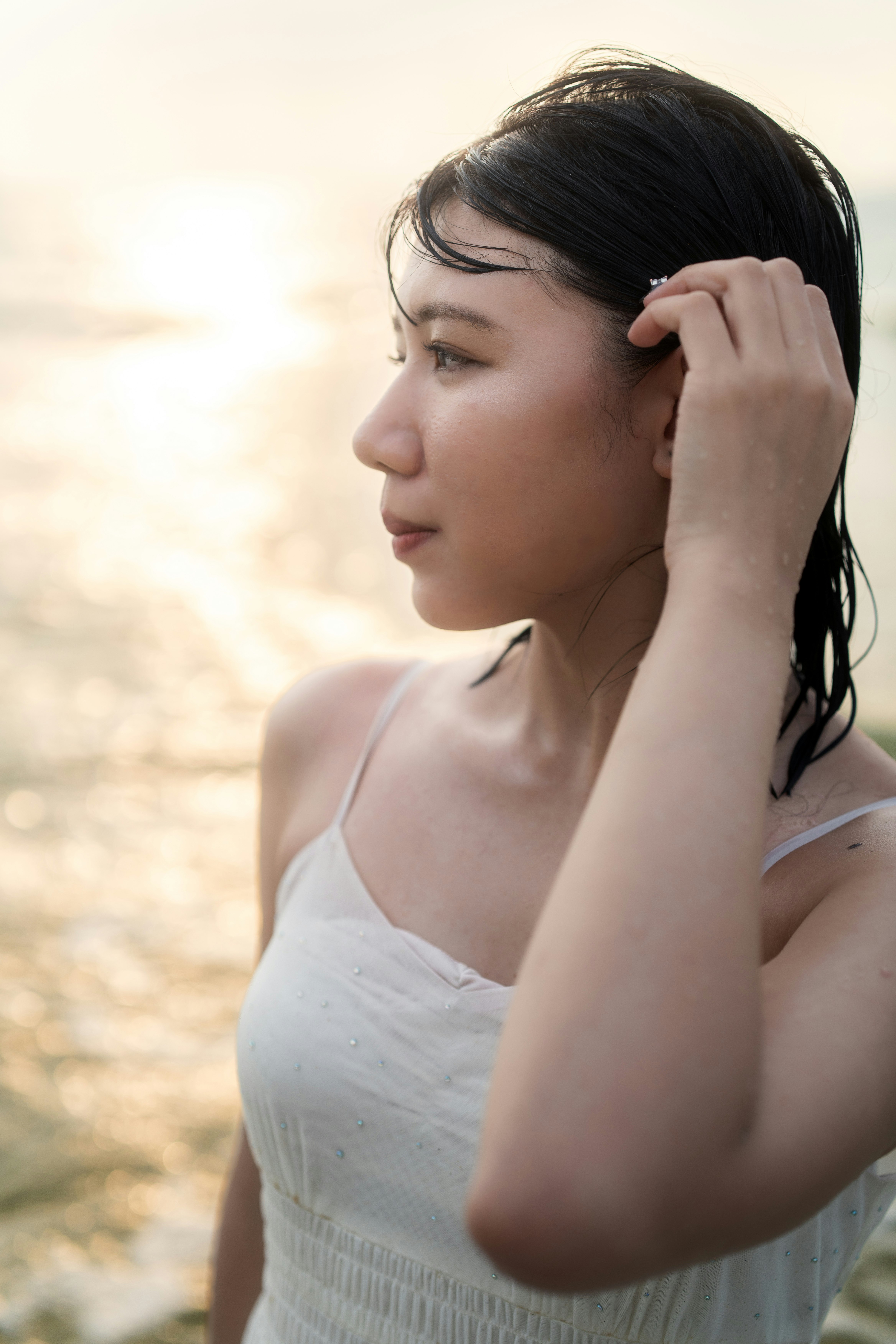夕日に照らされた横顔の女性が髪を耳にかける