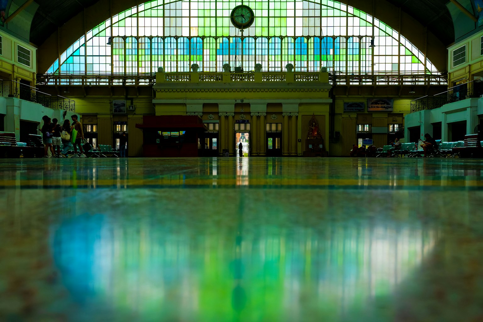 Intérieur spacieux d'une gare avec de grandes fenêtres en vitrail coloré et un sol brillant