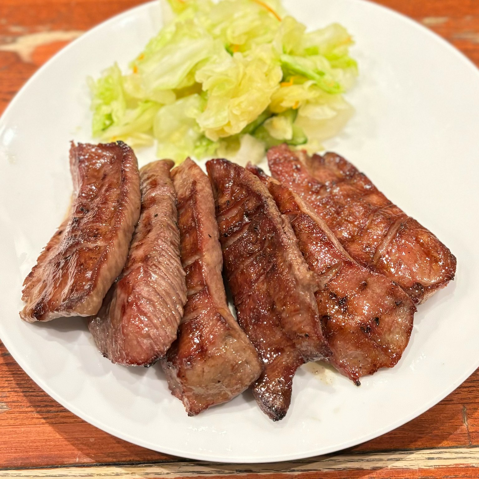 Carne a la parrilla servida en un plato con una guarnición de lechuga
