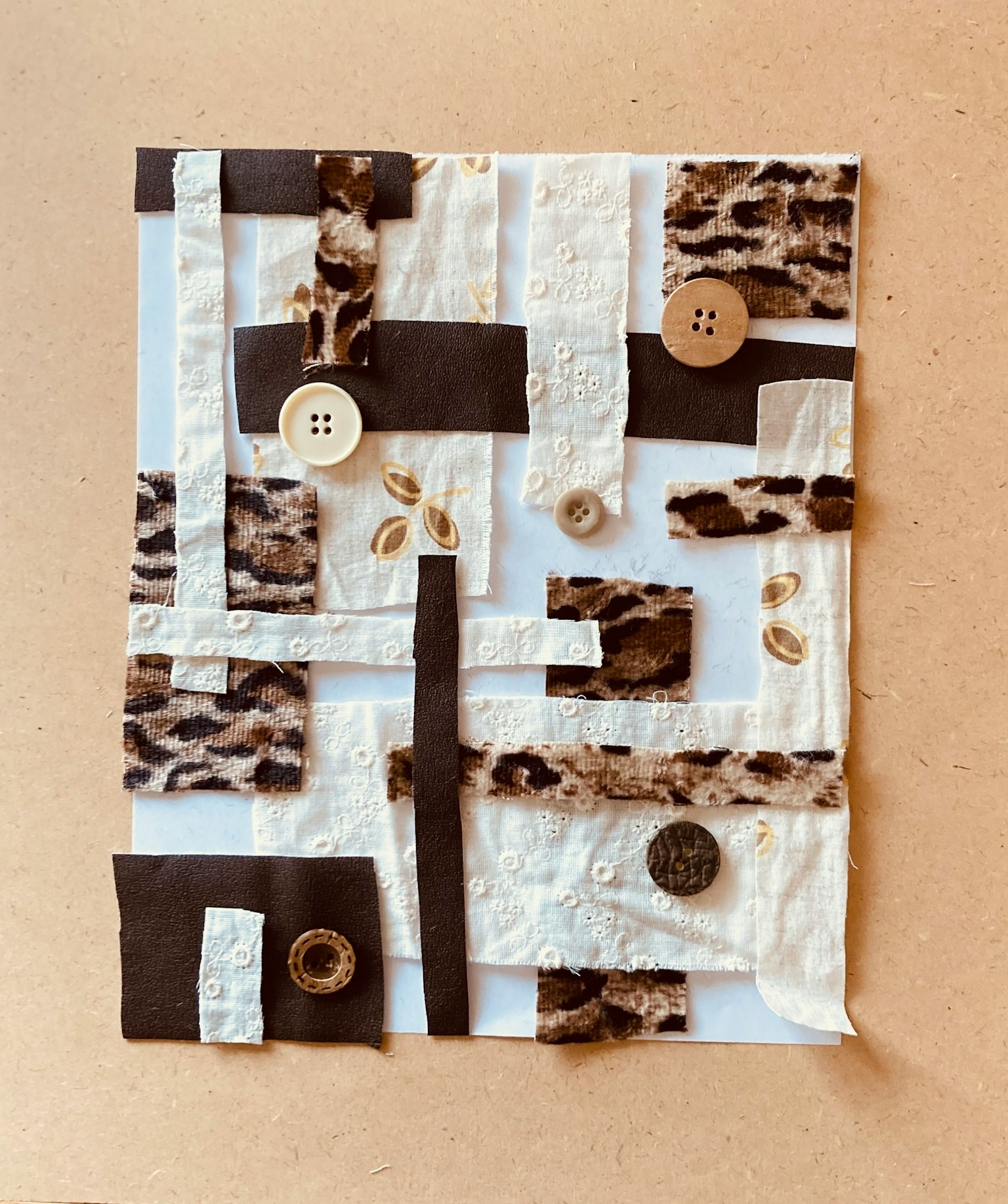 使用白色和棕色材料的拼貼藝術作品，具有鈕扣和獨特的質感
