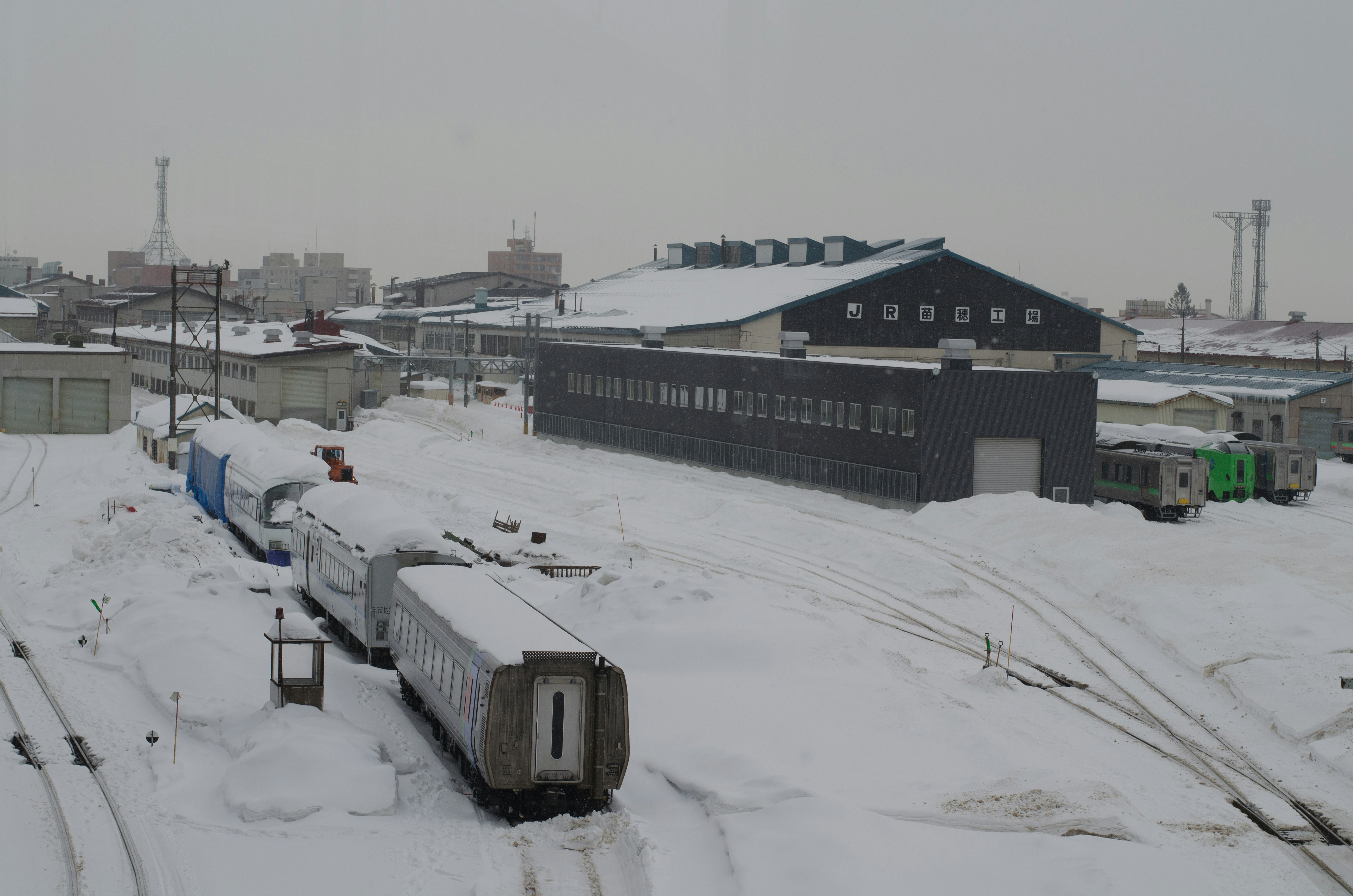 雪の積もる工業地帯の線路と貨車のあるヤード