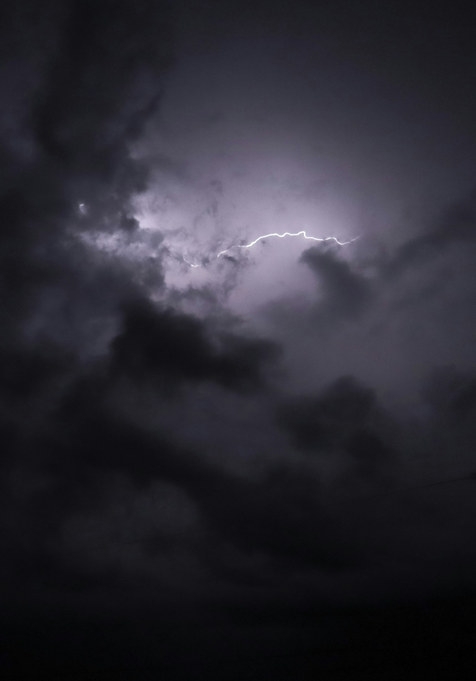 Cielo scuro con fulmini che illuminano nuvole minacciose