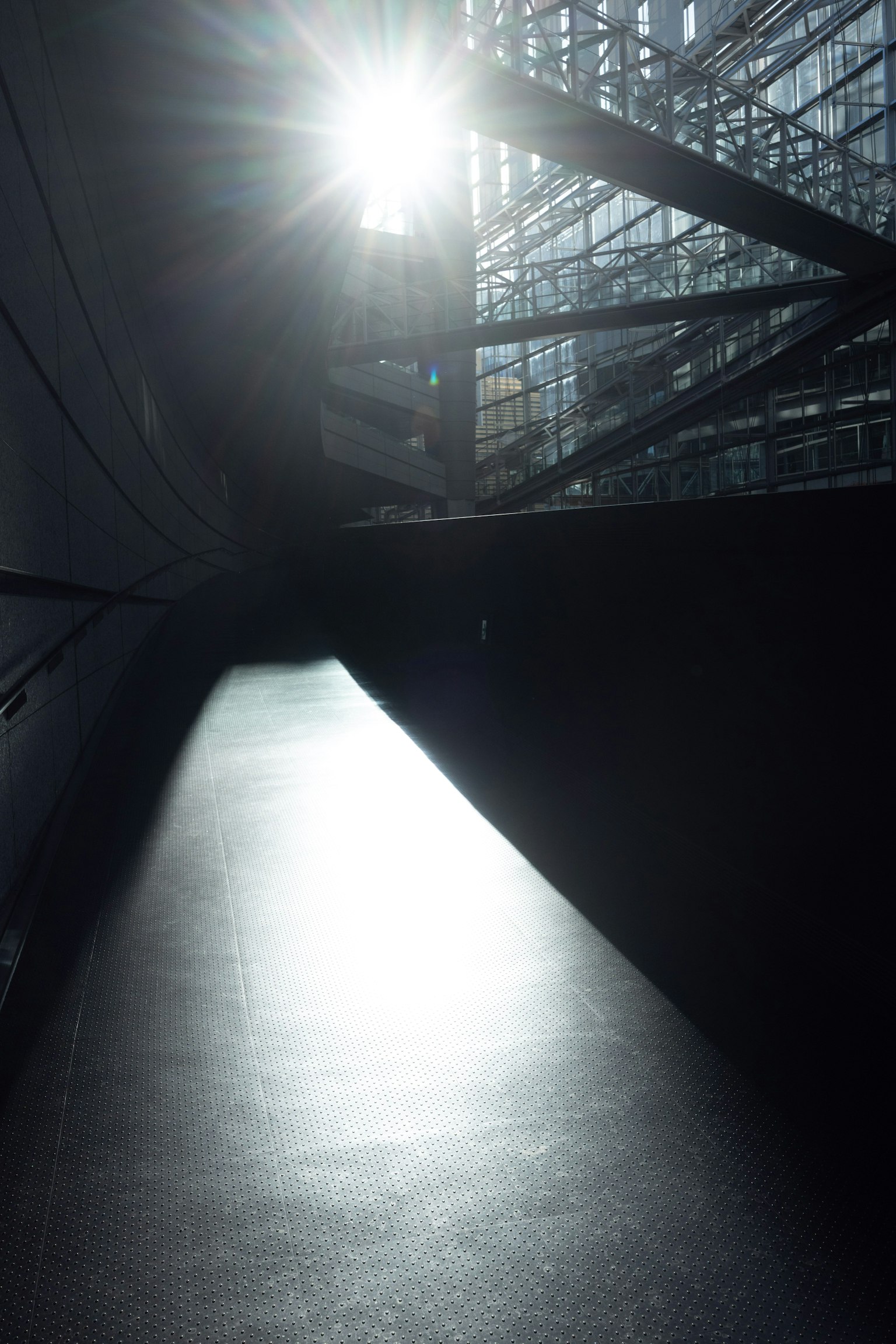 Interno di un edificio moderno con luce solare che entra superficie nera lucida e struttura in vetro