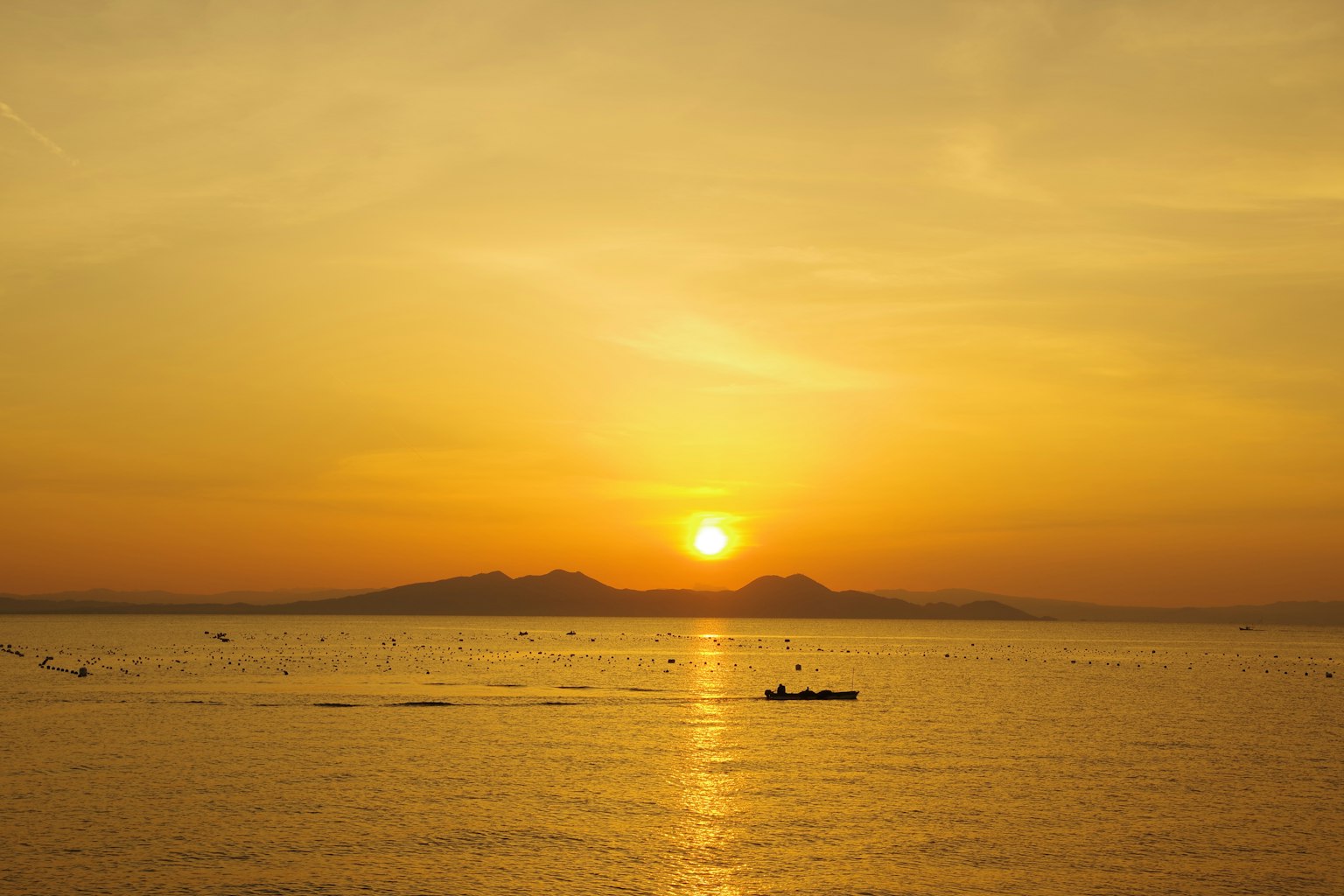 Pemandangan matahari terbenam yang indah dengan siluet gunung dan air tenang