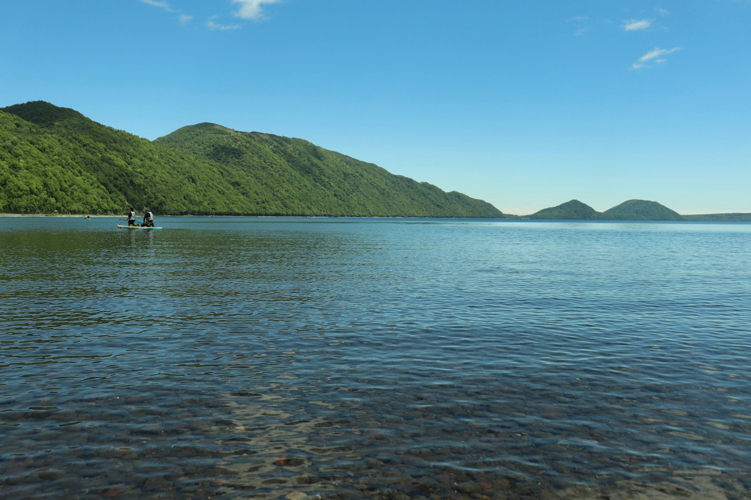 ทิวทัศน์สวยงามของน้ำสีฟ้าและภูเขาสีเขียวพร้อมเรือเล็ก