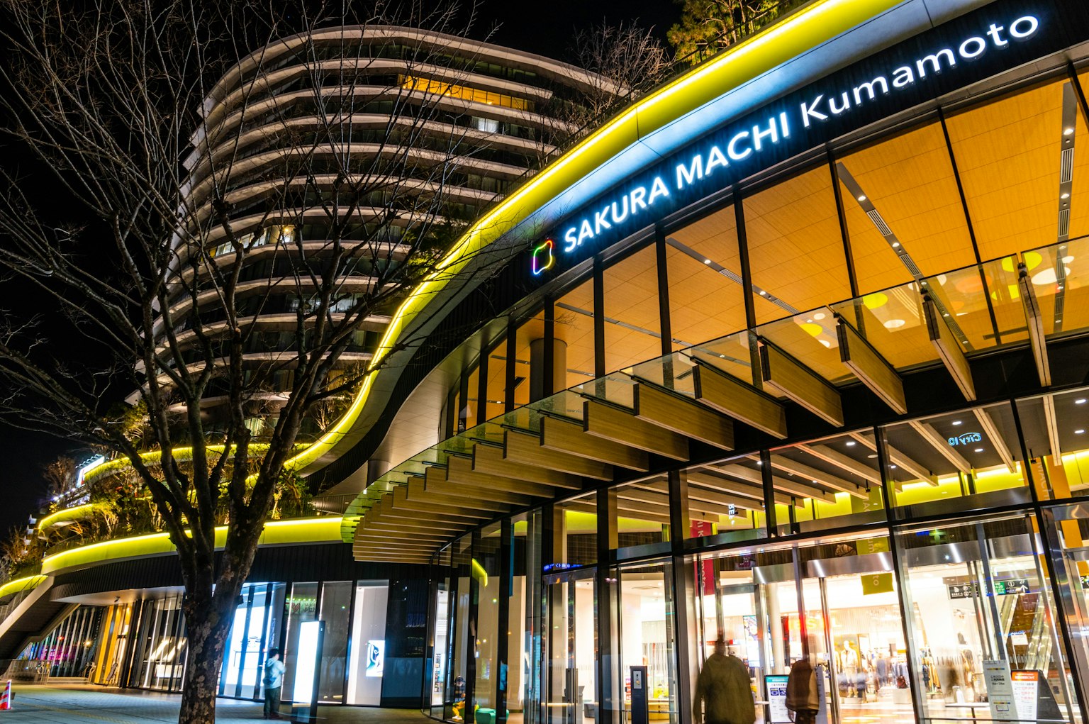 Edificio moderno di Sakura Machi Kumamoto di notte con illuminazione brillante