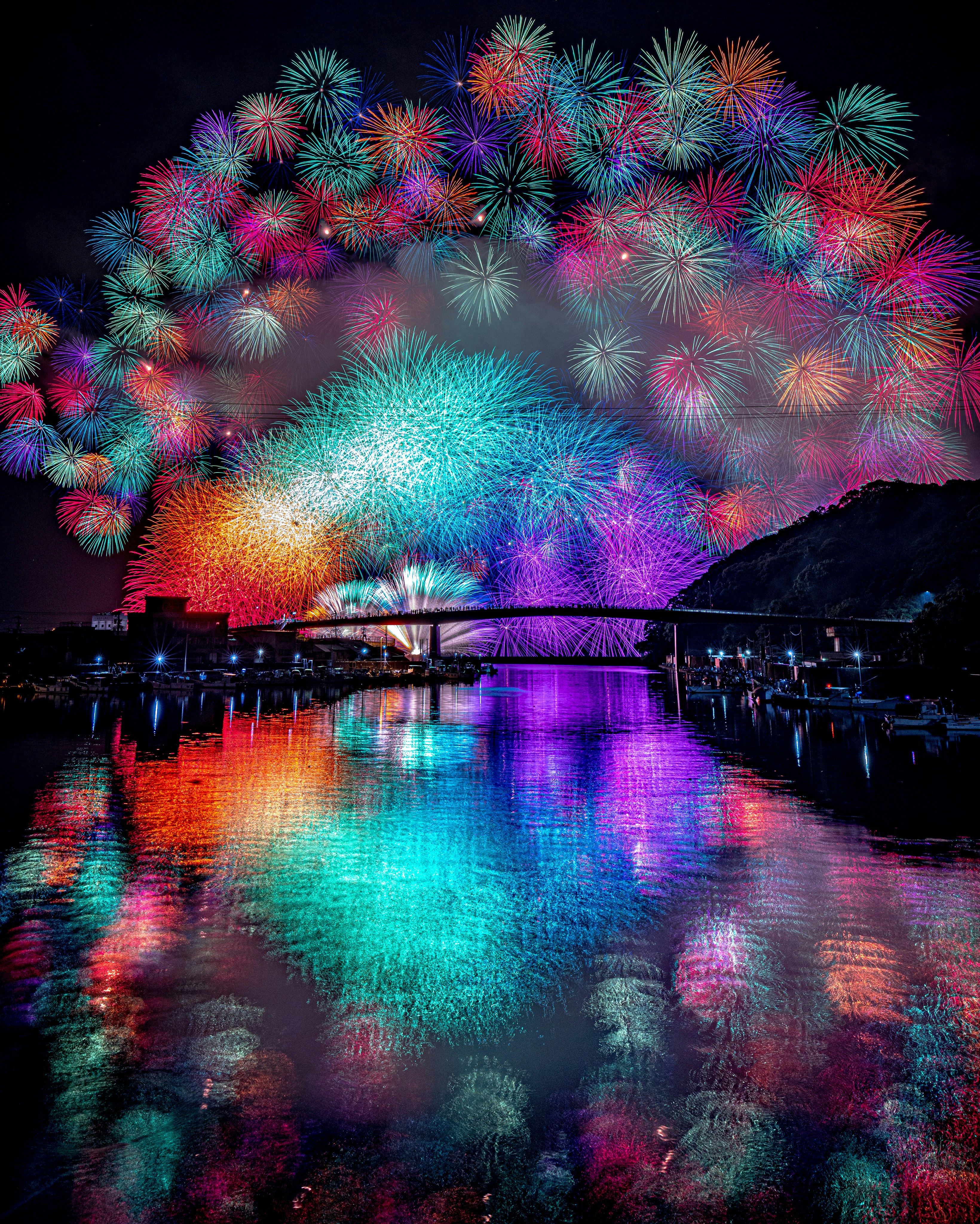 bunte Feuerwerke spiegeln sich nachts im Fluss bei einem Laternenfest