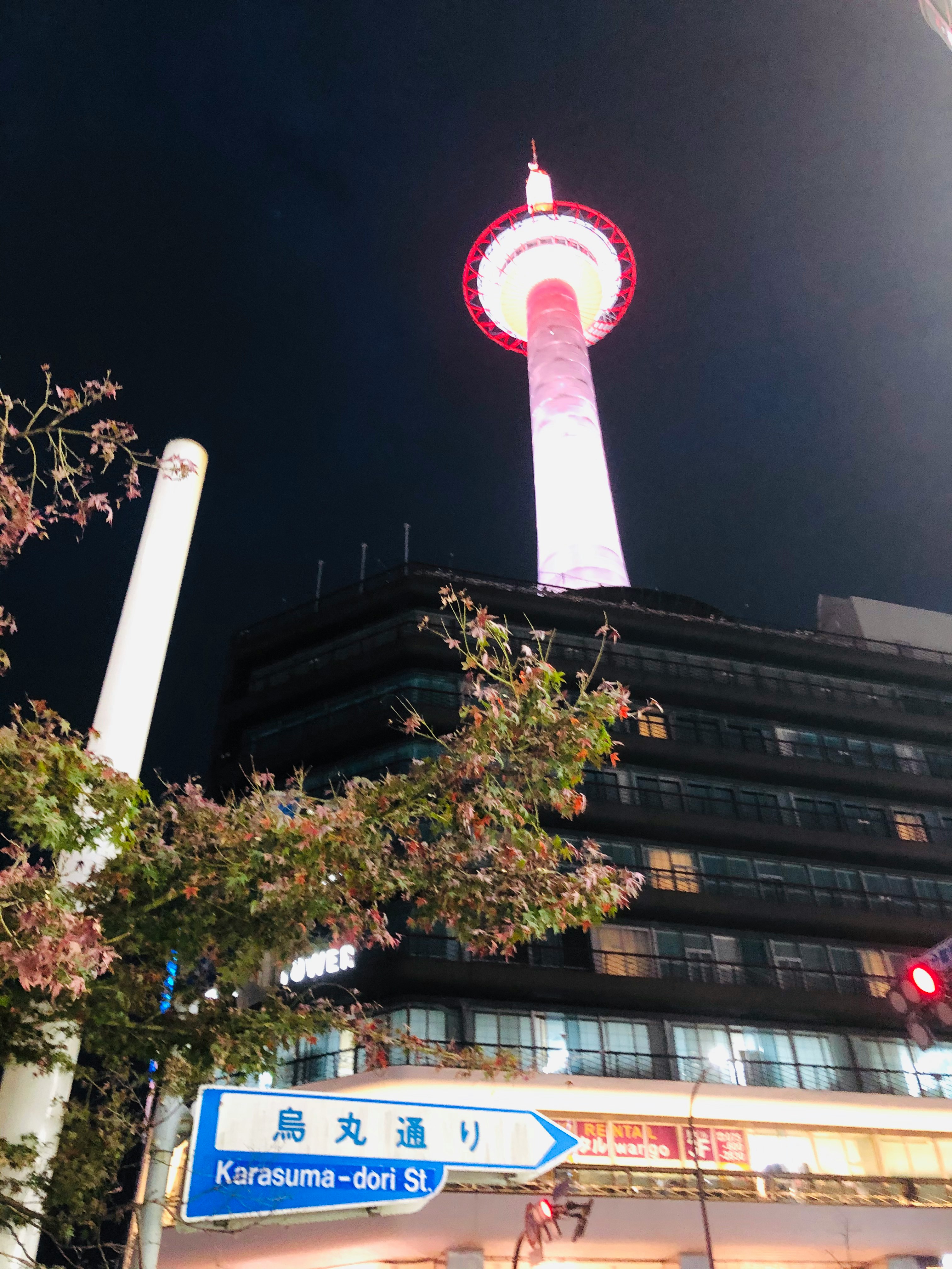 夜晚街角，蓝色“烏丸通”路牌与发光塔