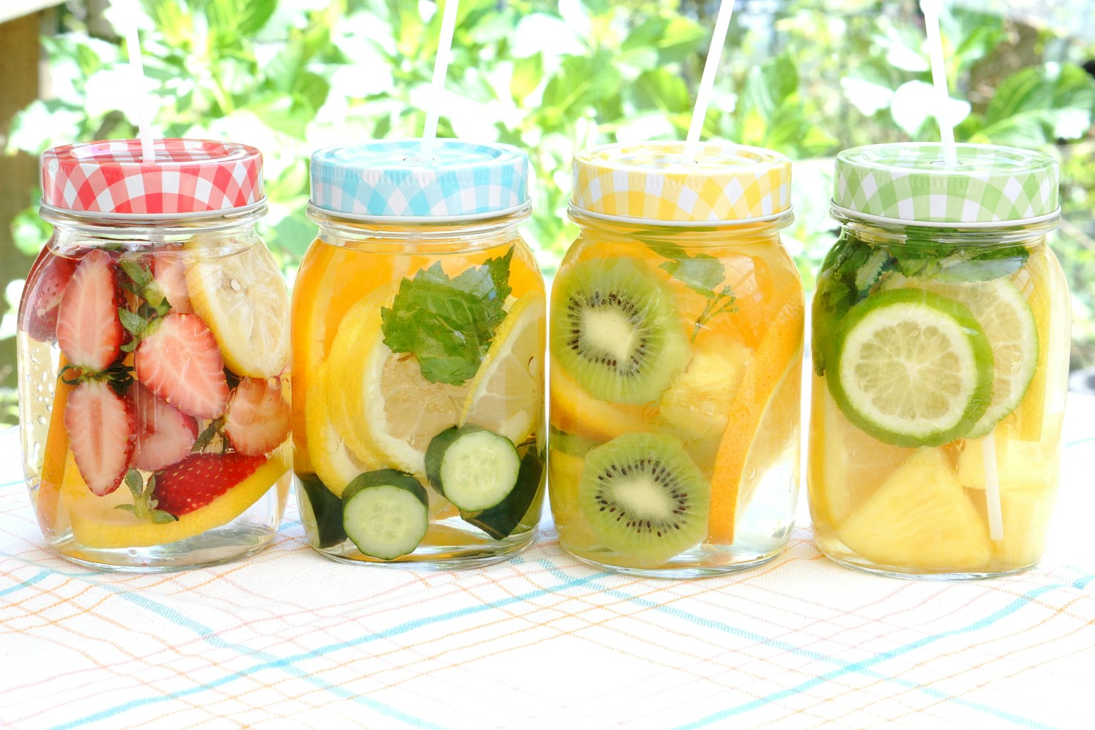 Bocaux d'eau infusée aux fruits et aux herbes alignés à l'extérieur
