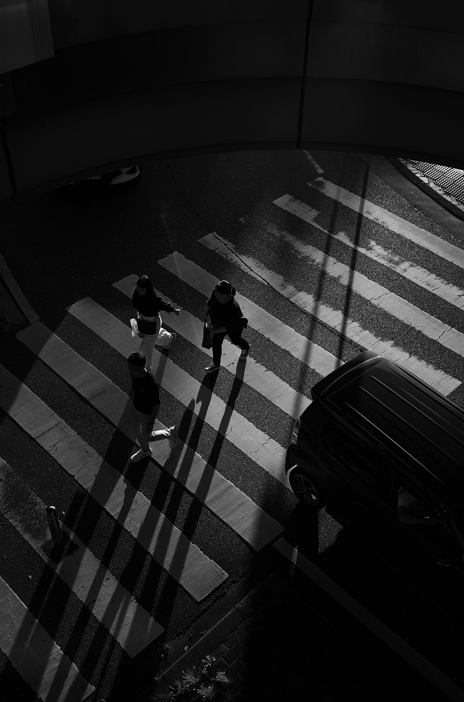 Shadows of pedestrians crossing a black and white striped crosswalk