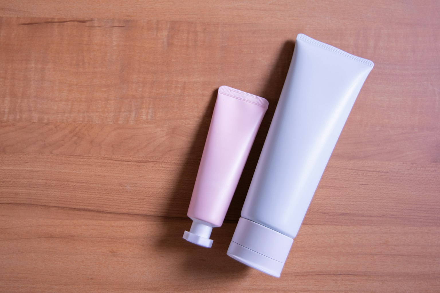 Tubes rose et blanc posés sur une table en bois