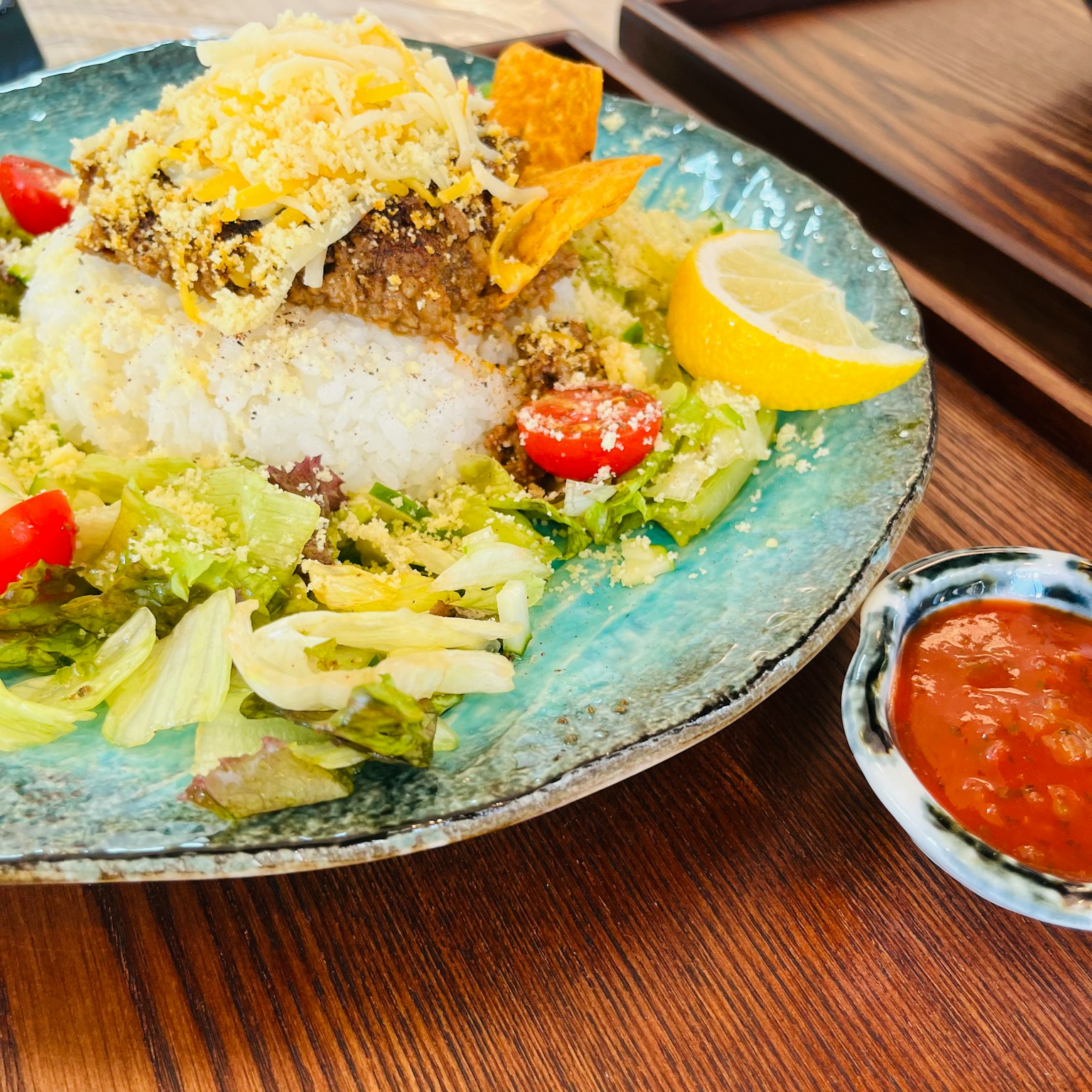 Ein Teller Reis und Salat mit Zitrone und Salsa-Sauce daneben