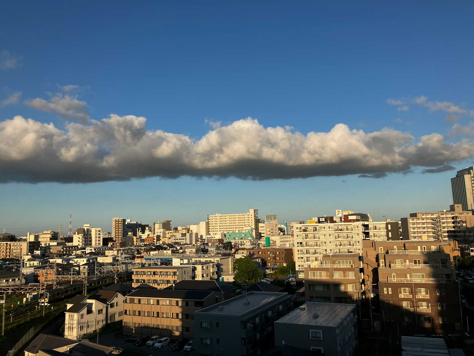 Urban landscape with blue sky and clouds featuring high-rise buildings and houses