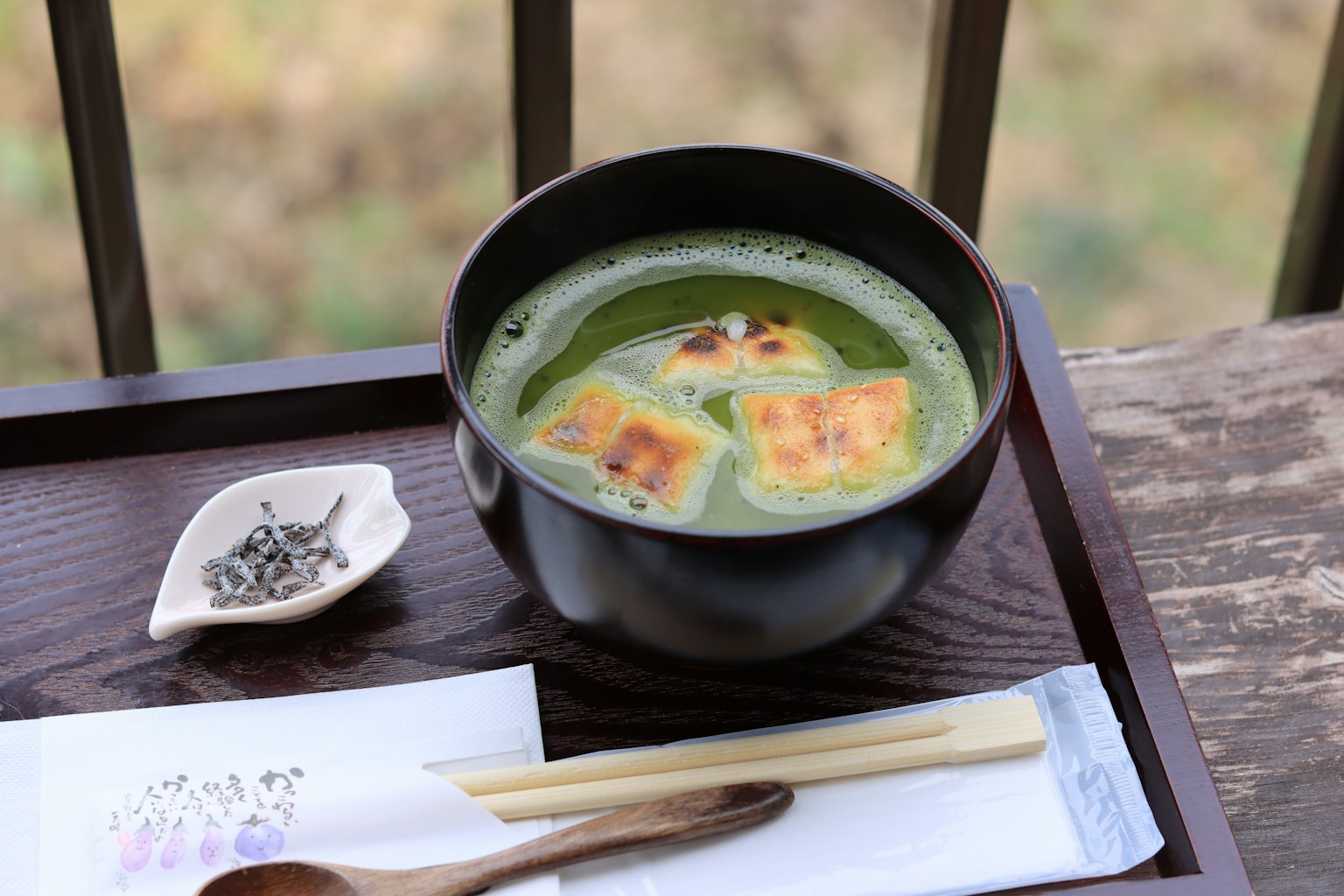 Image d'un bol noir avec de la soupe au thé vert et du tofu grillé