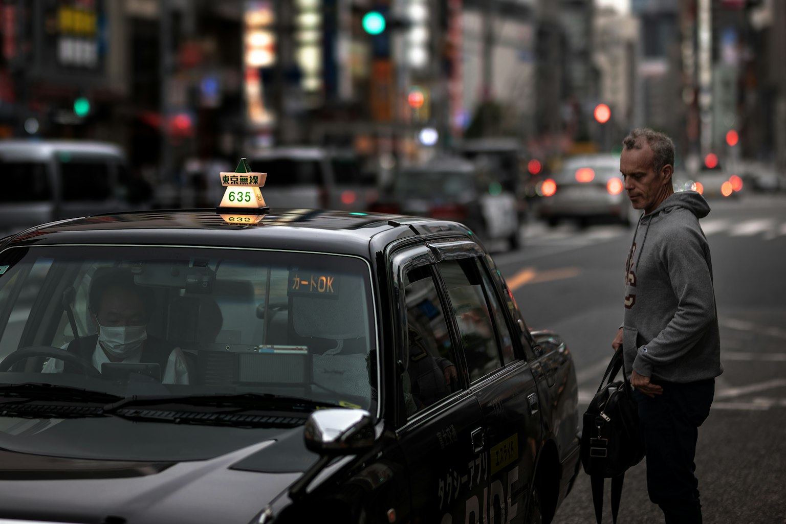 Un hombre esperando un taxi en una calle bulliciosa de la ciudad por la noche