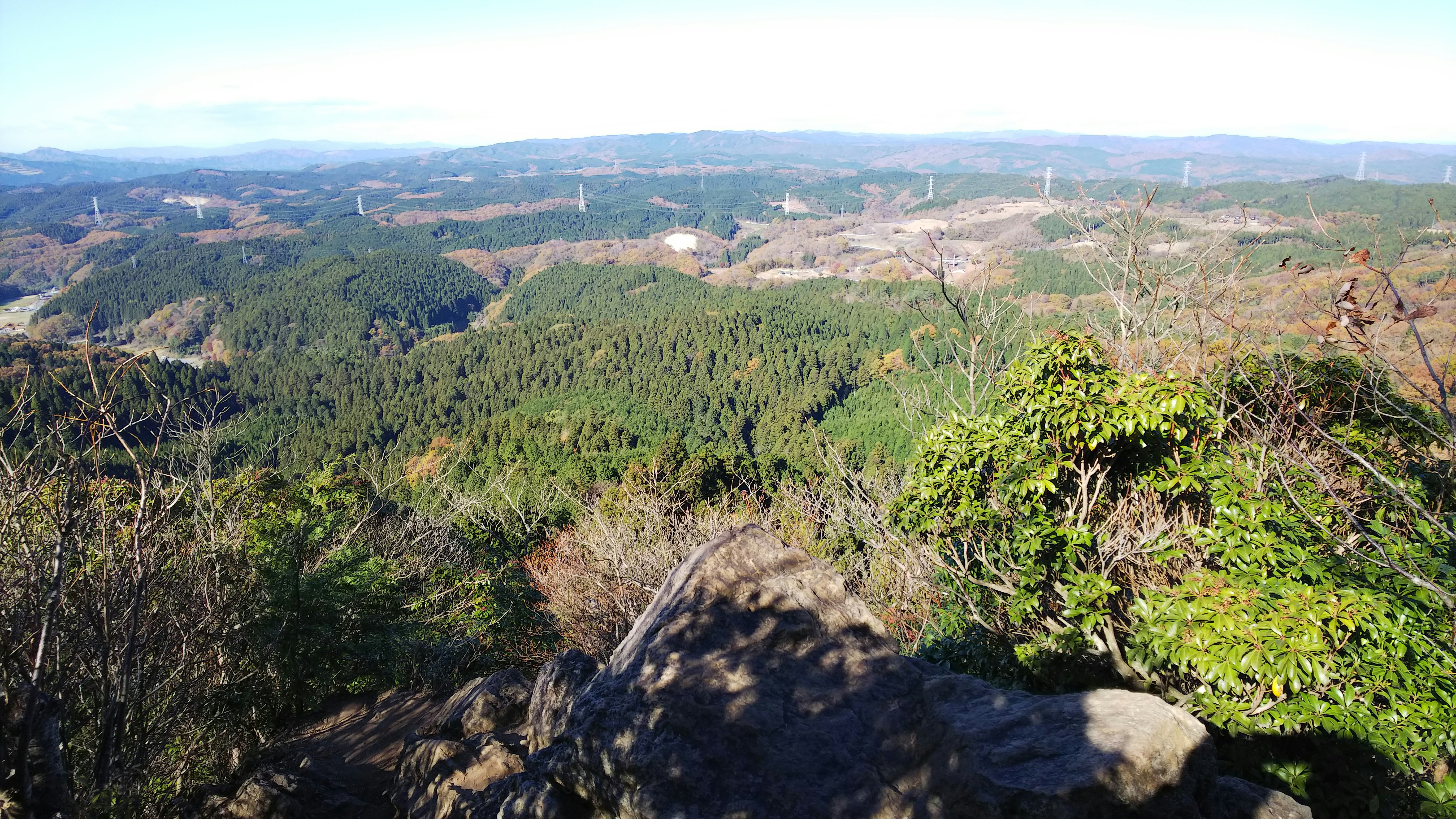 Vast landscape view from mountain peak lush green forests and distant mountains visible