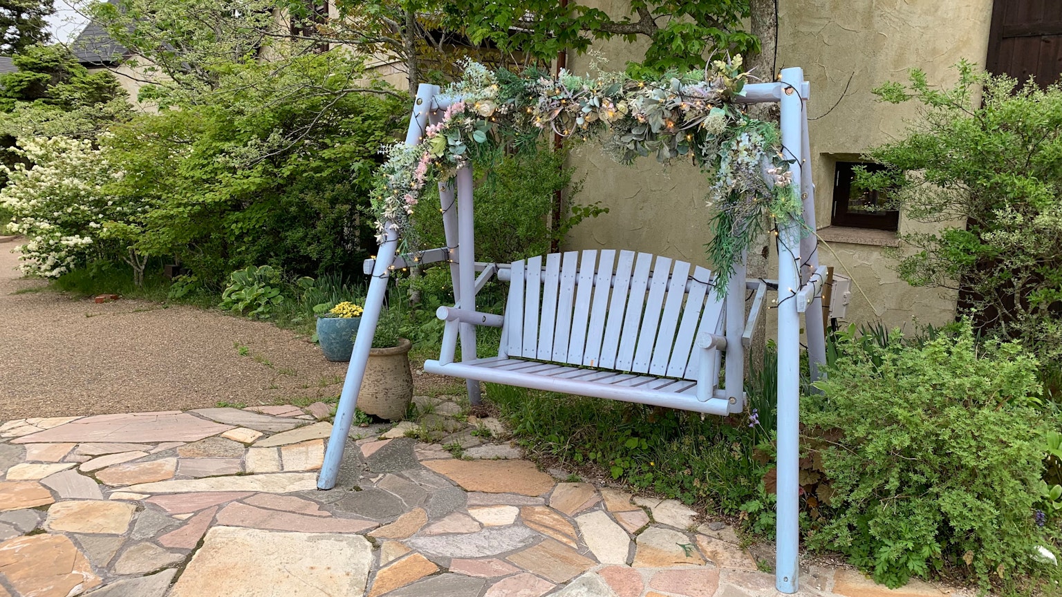 Une balançoire bleue décorée de fleurs dans un jardin