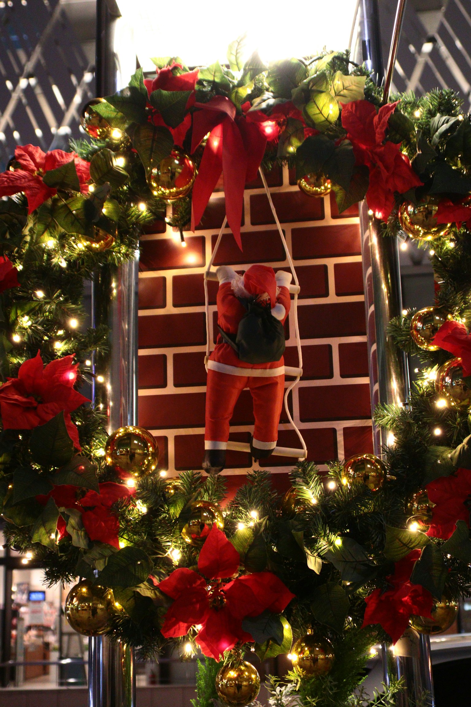 Corona di Natale con Babbo Natale che scende da un camino circondato da luci