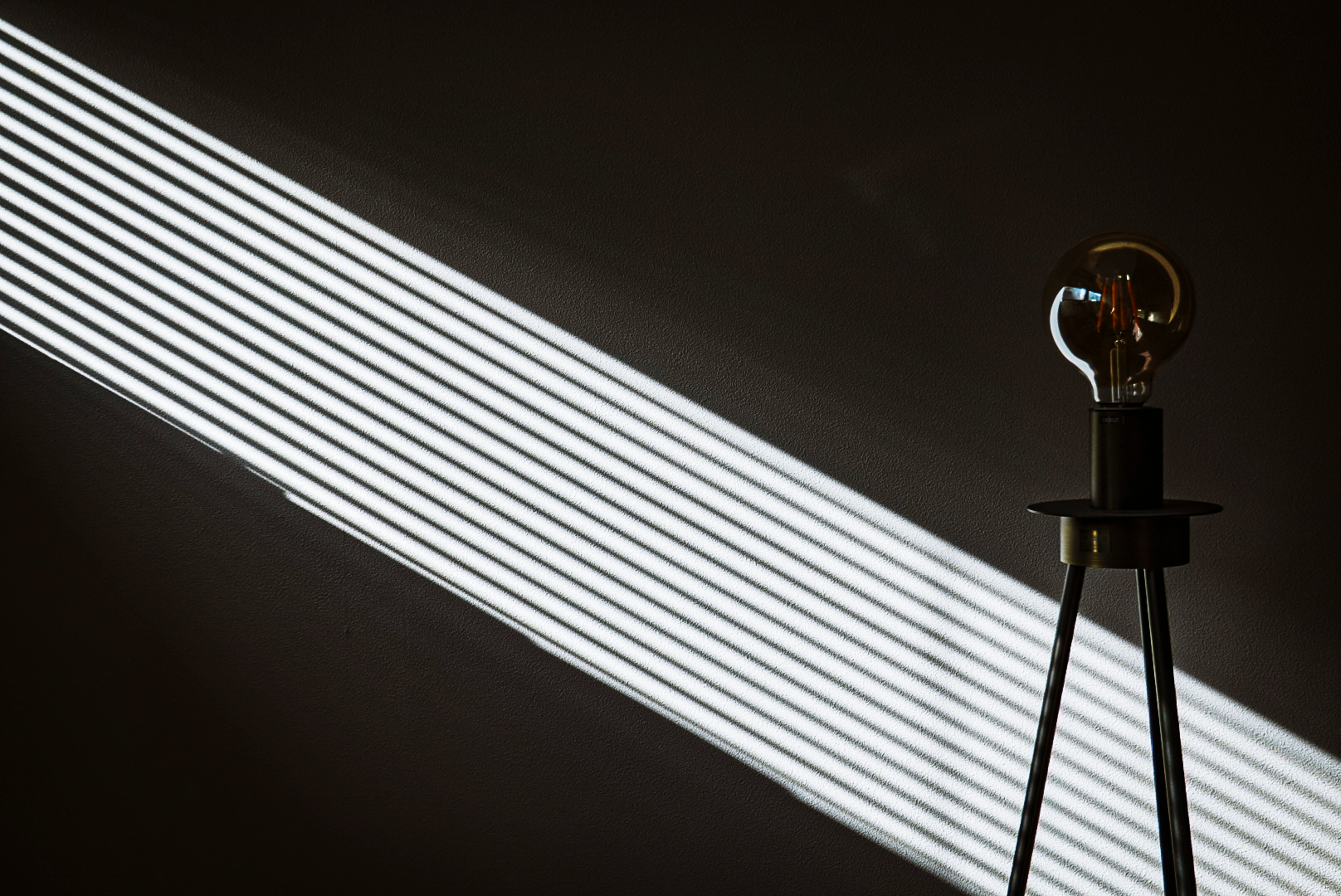 斜めに伸びる光のラインと電球のあるスタンドの静物