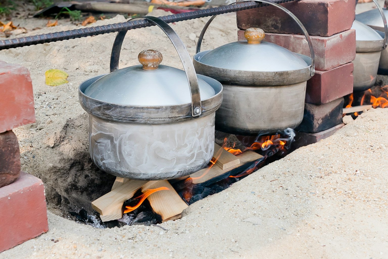 Scène de cuisine en plein air avec des casseroles en métal sur une flamme ouverte