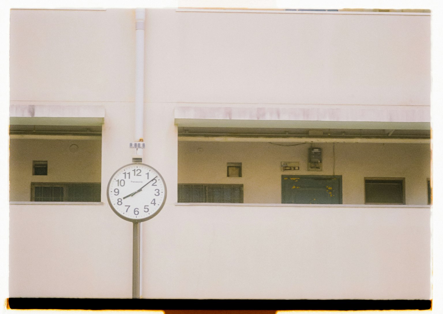 Large clock mounted on a white wall with windows