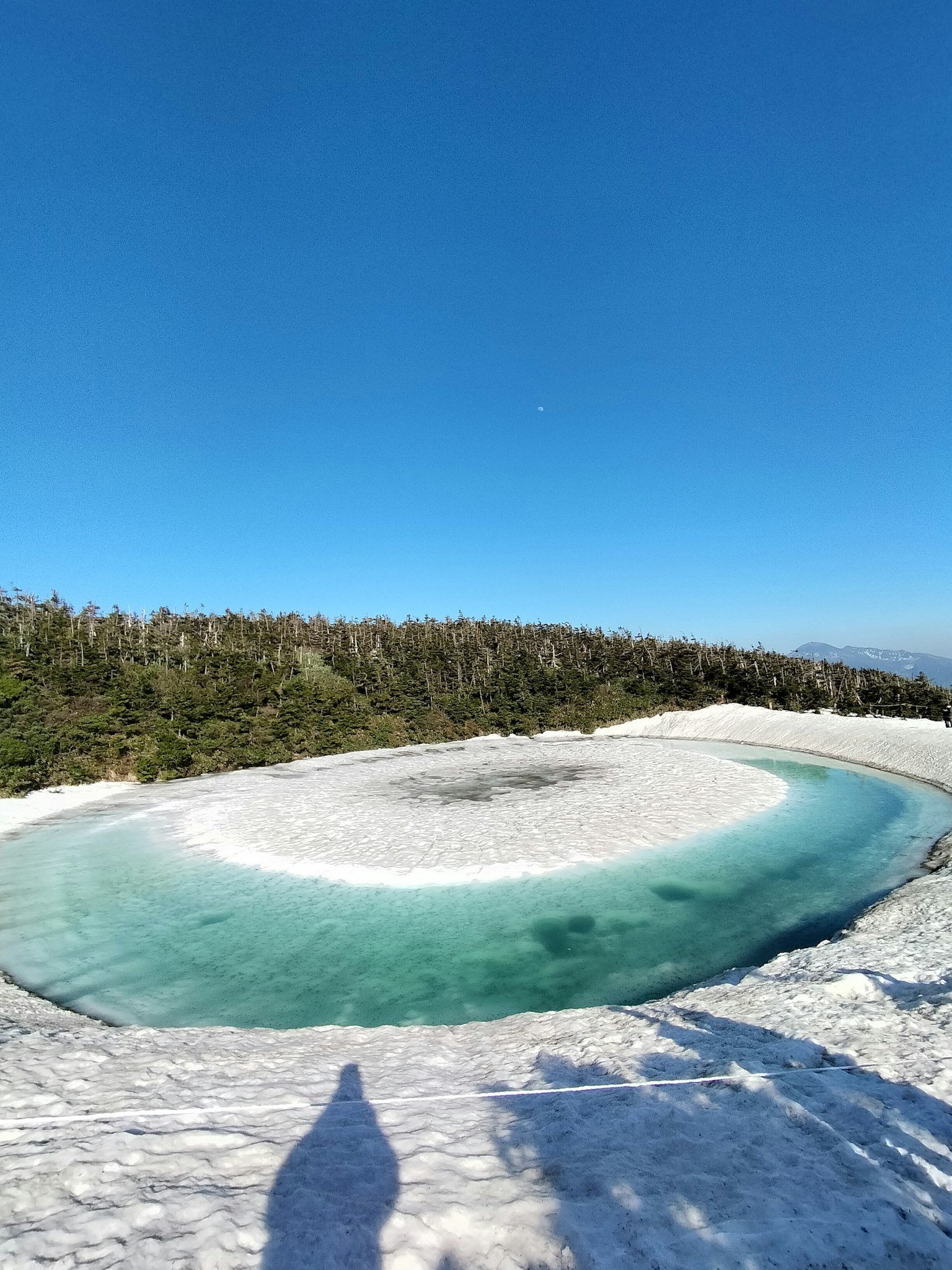 Pemandangan indah danau biru dikelilingi salju dan hutan
