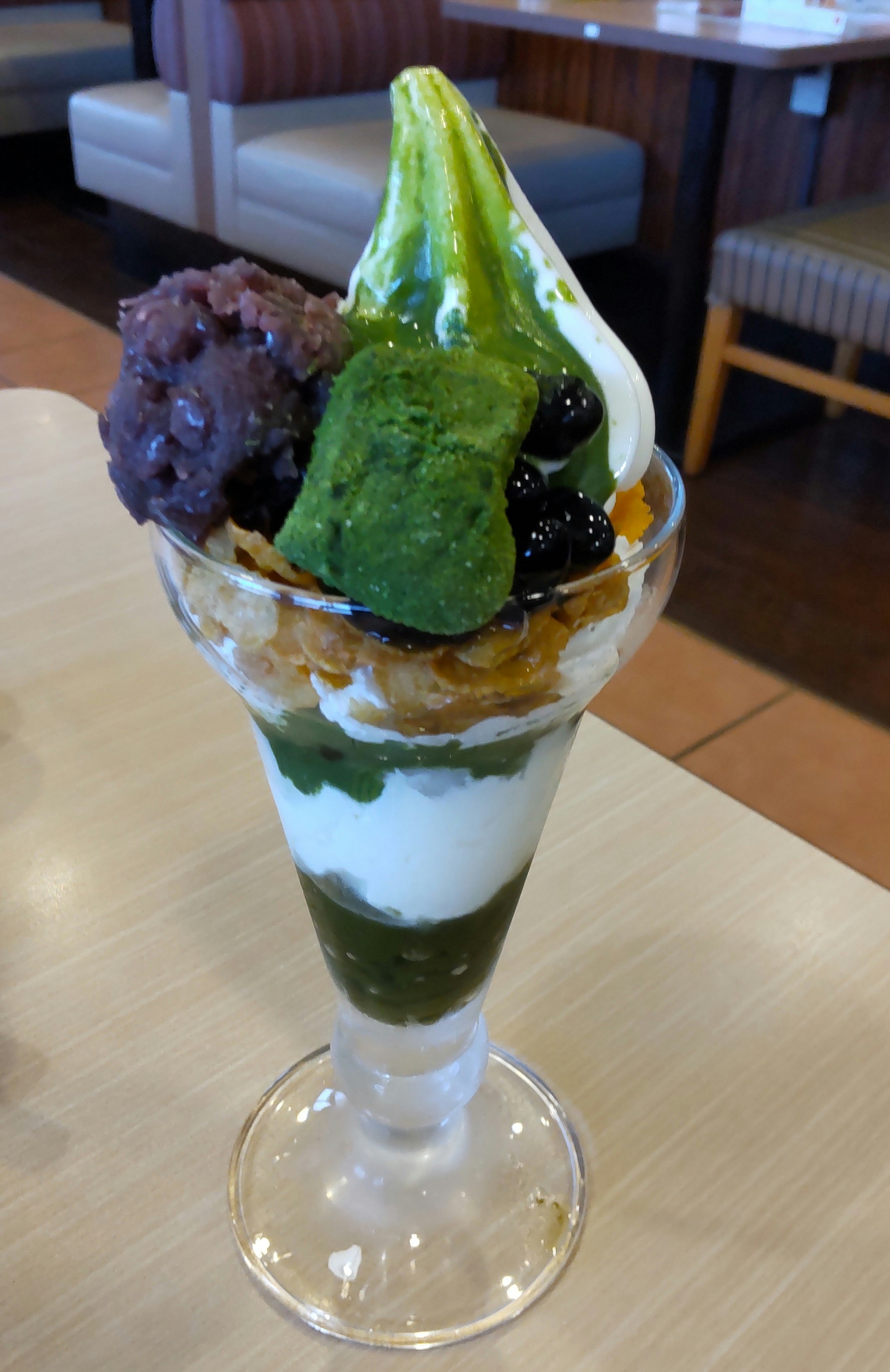 抹茶パフェのグラスにのった緑のアイスとトッピング