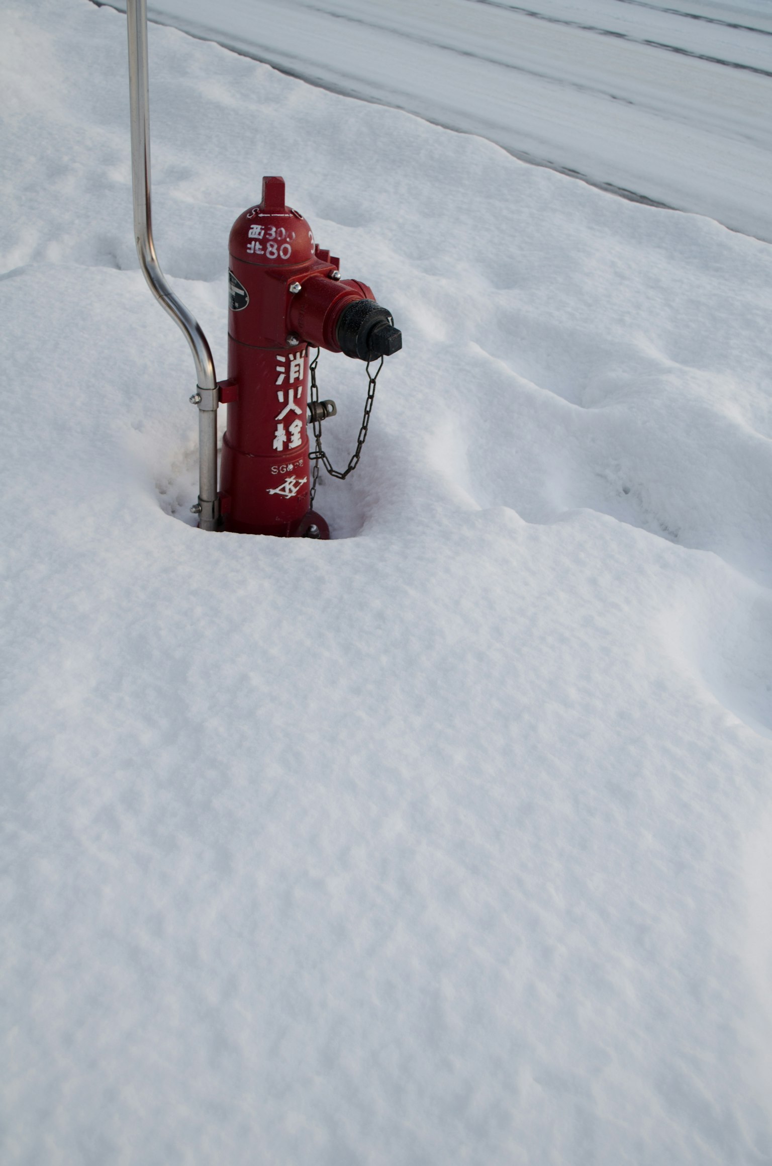 Imagen de un hidrante rojo parcialmente enterrado en la nieve