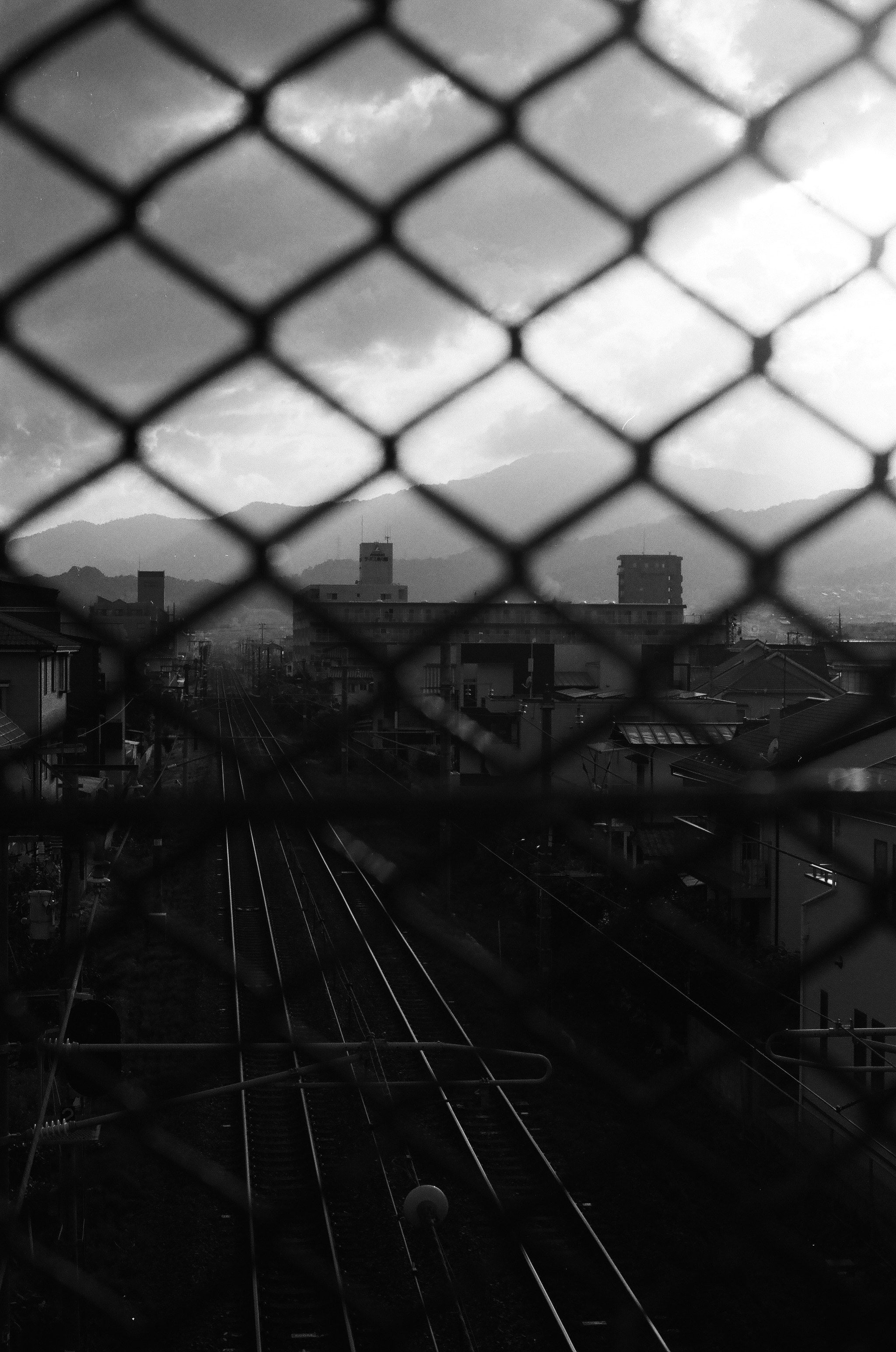 フェンス越しの線路と街並みの夕暮れ風景