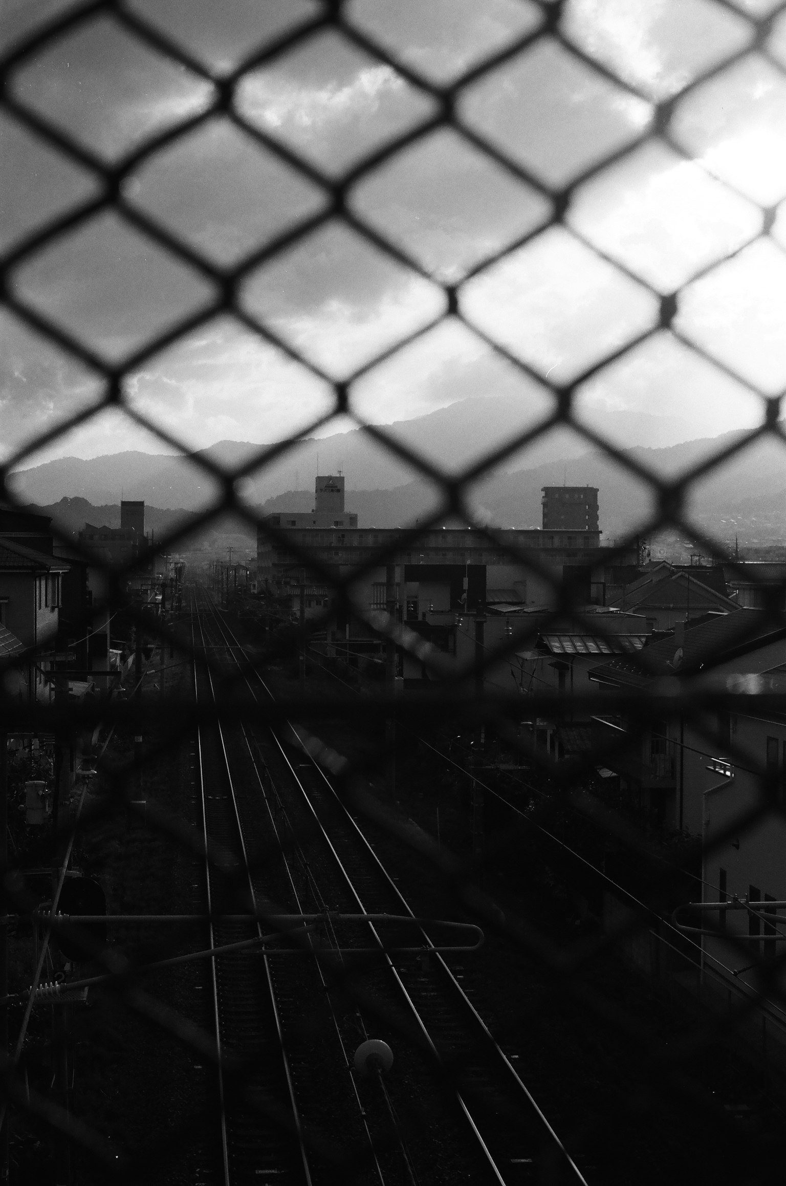 鉄道の線路と都市の景色を背景にした網目のフェンス