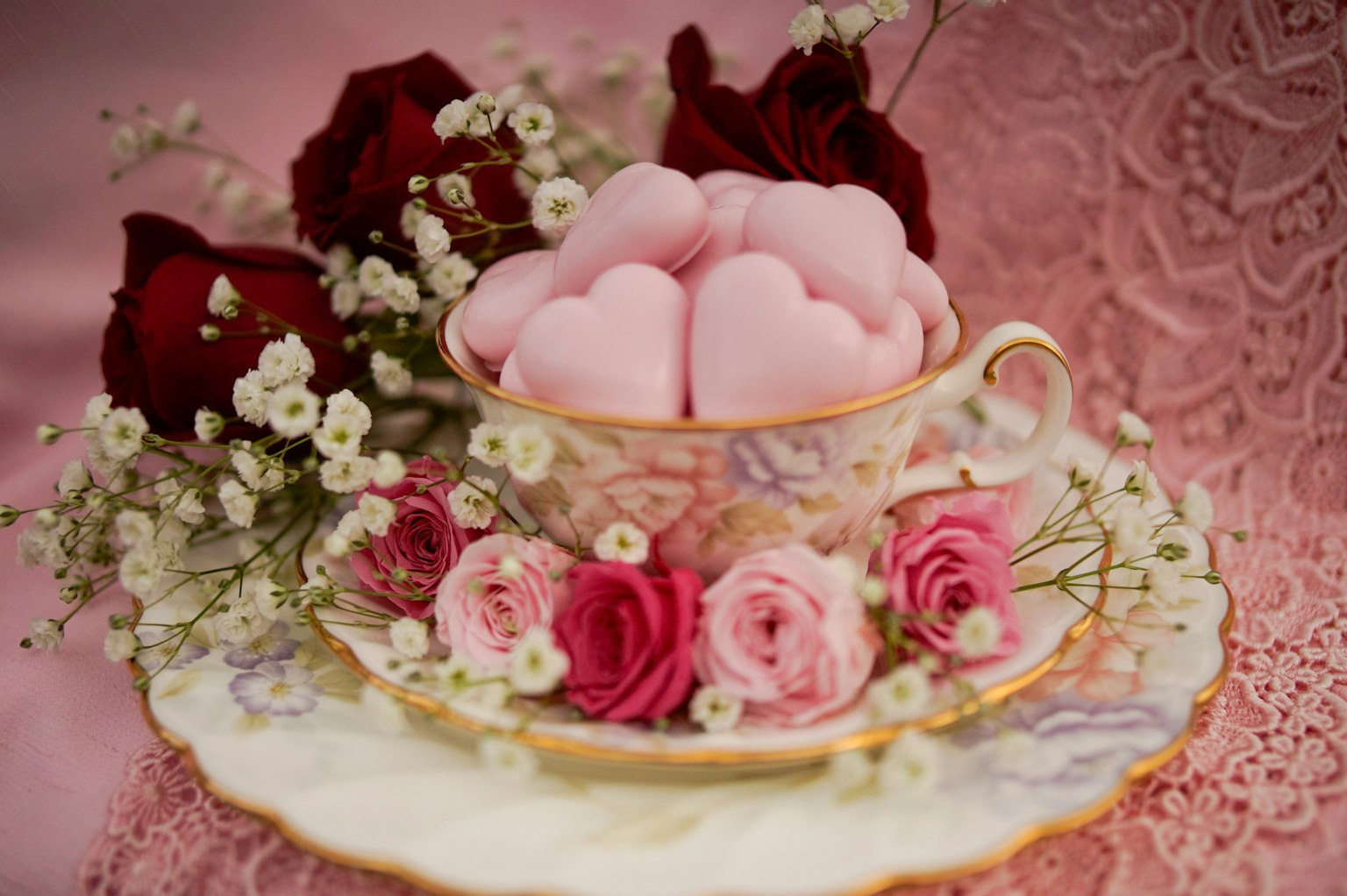 Malvaviscos en forma de corazón rosa en una taza con flores alrededor