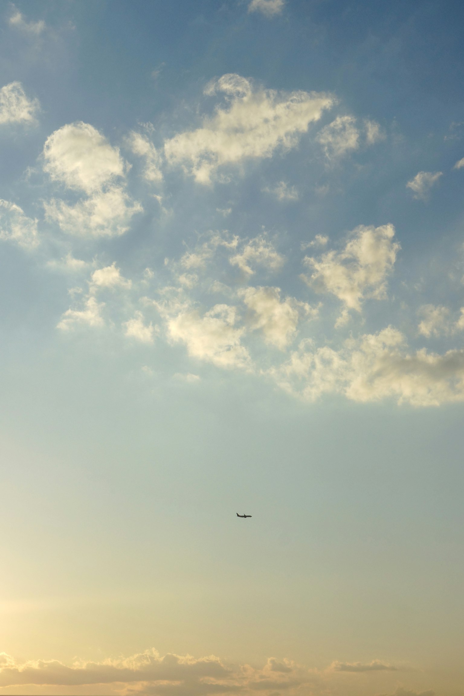 푸른 하늘에 떠 있는 흰 구름과 작은 비행기