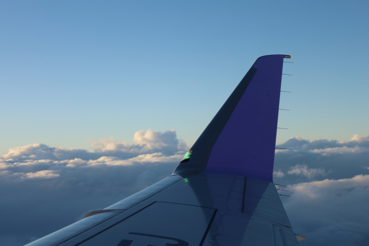 飛機尾翼紫色設計與多雲天空