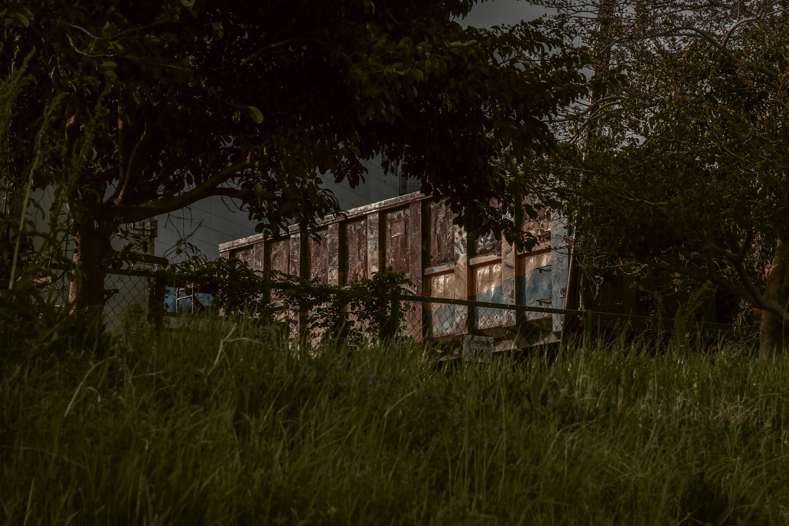 Alte Holzhütte auf einer grasbewachsenen Fläche unter einem dunklen Himmel