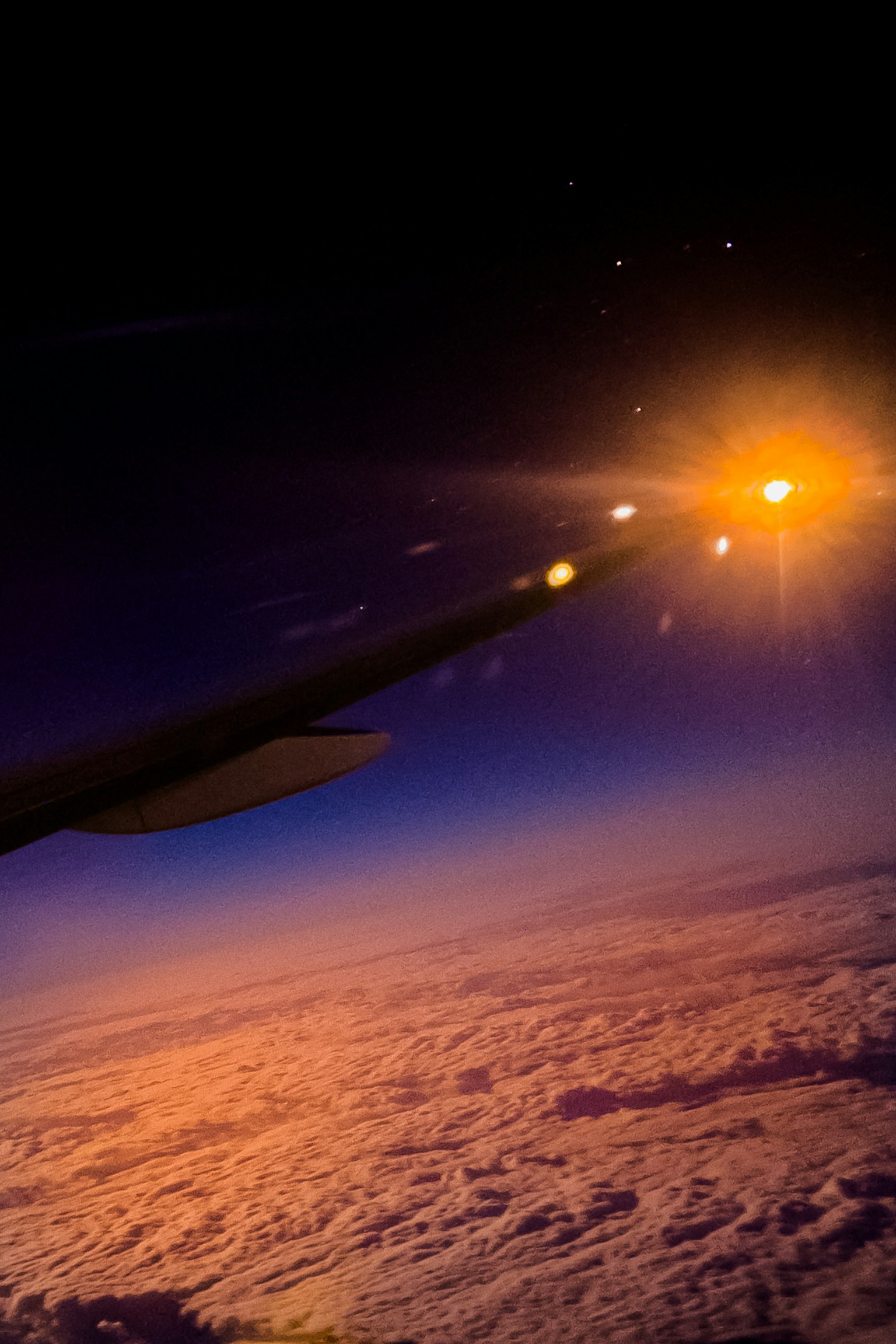 Ala di aereo con luce arancione brillante sopra le nuvole