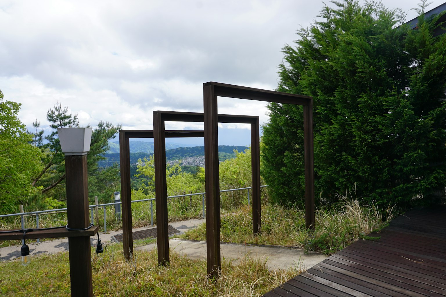 Square wooden frames amidst greenery with a distant view