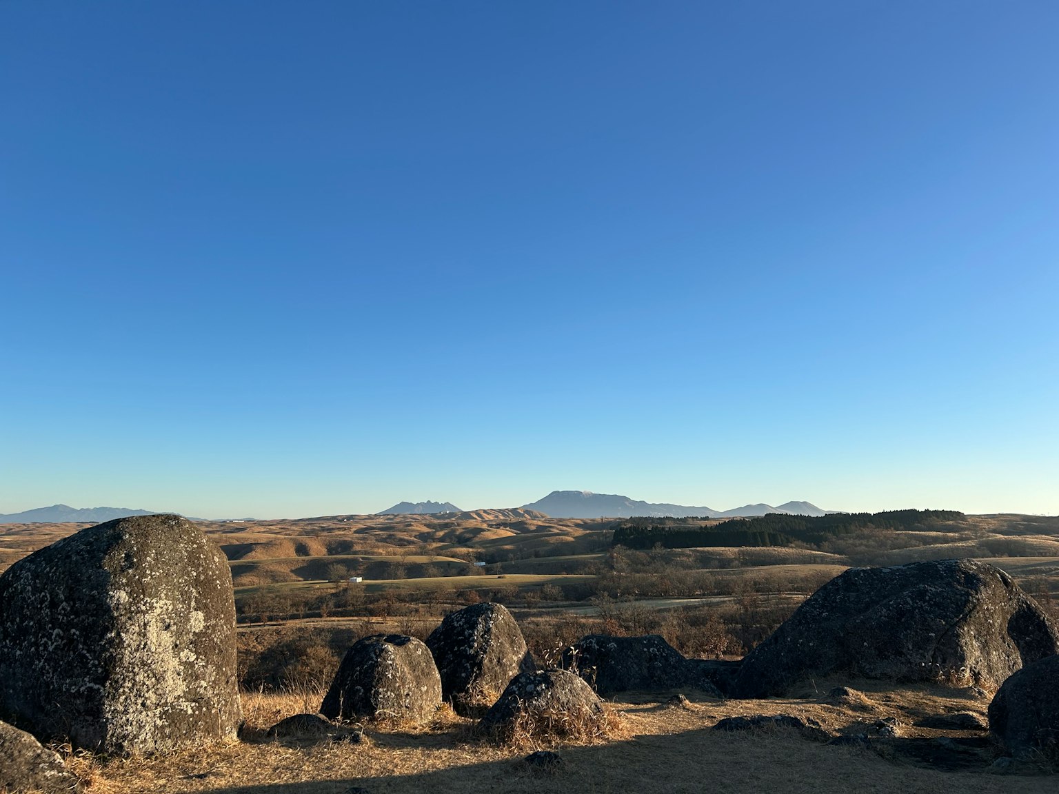 Landscape featuring large rocks with vast plains and distant mountains