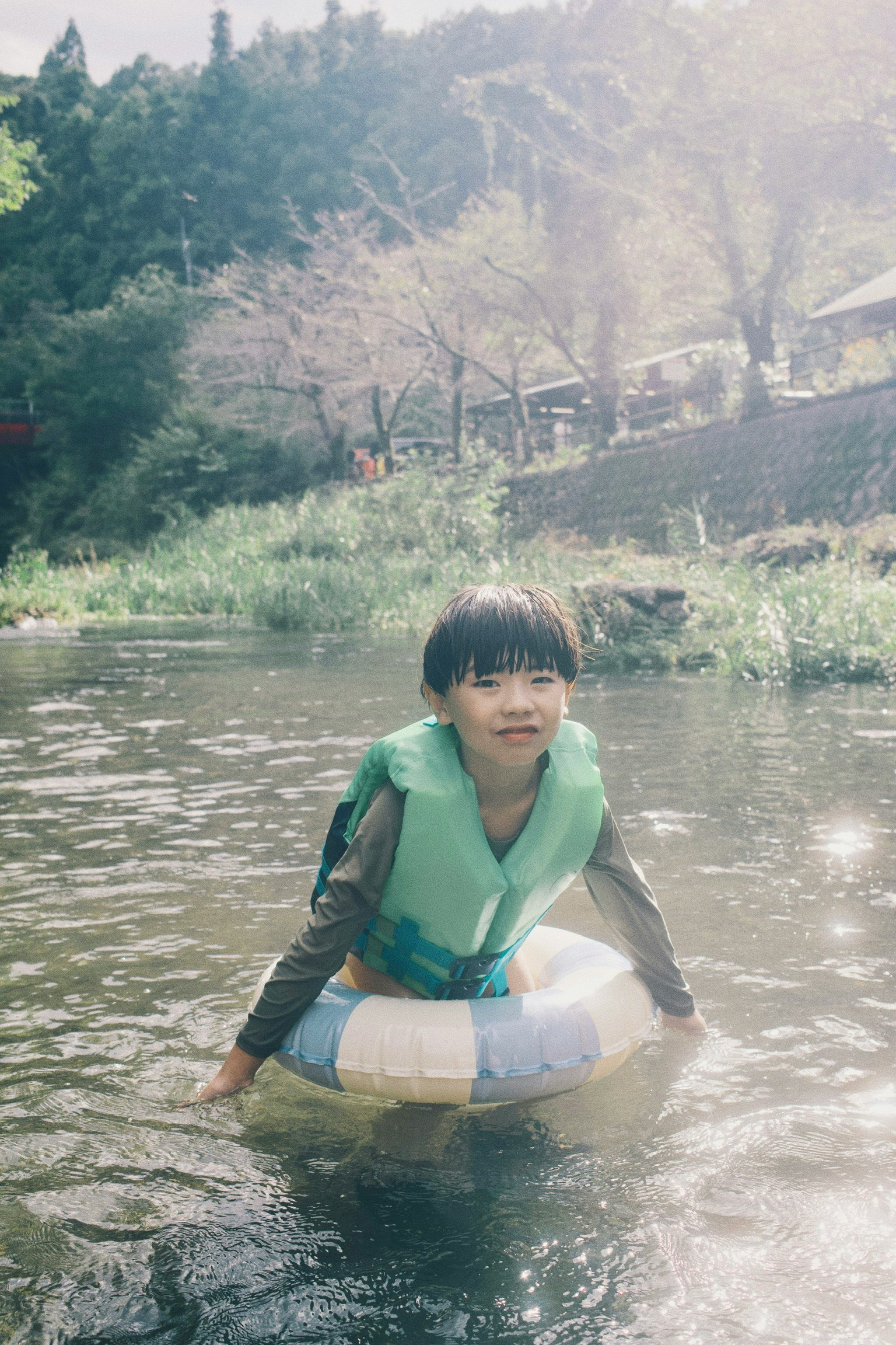 niño sonriente en un flotador junto a un río