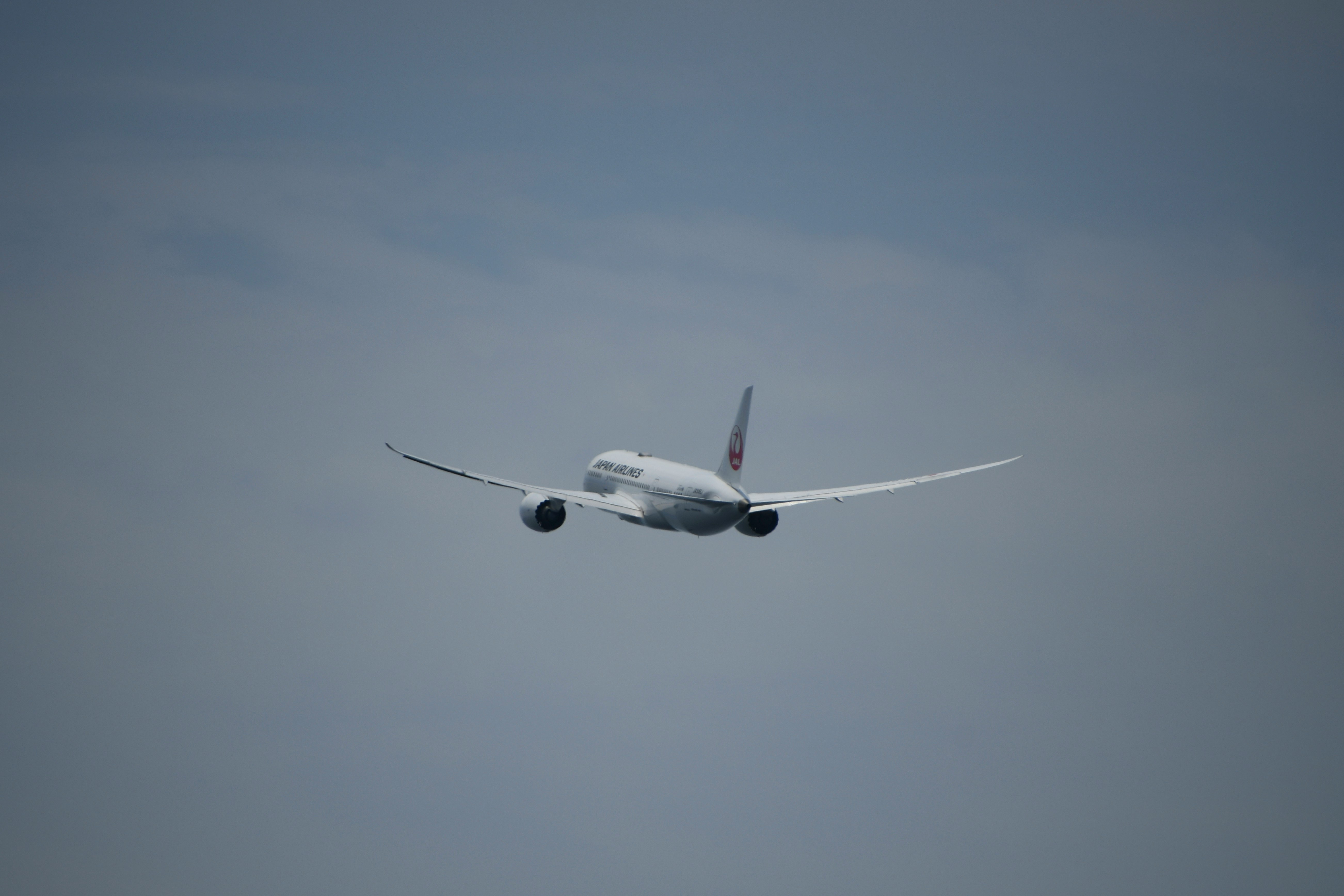 雲の間を飛ぶ旅客機の機首と翼
