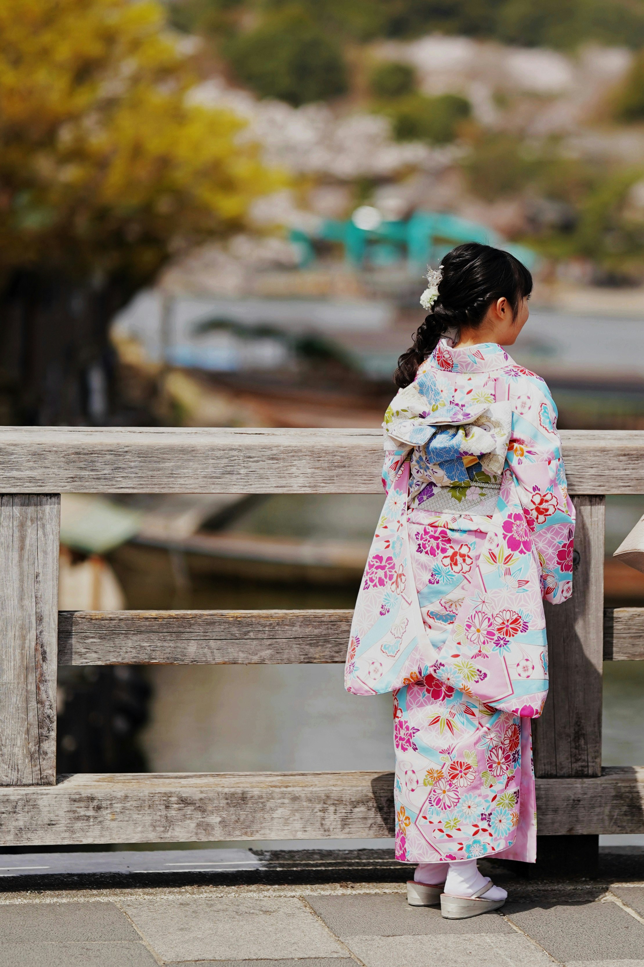 A child in kimono in Arashiyama with spring cherry blossoms