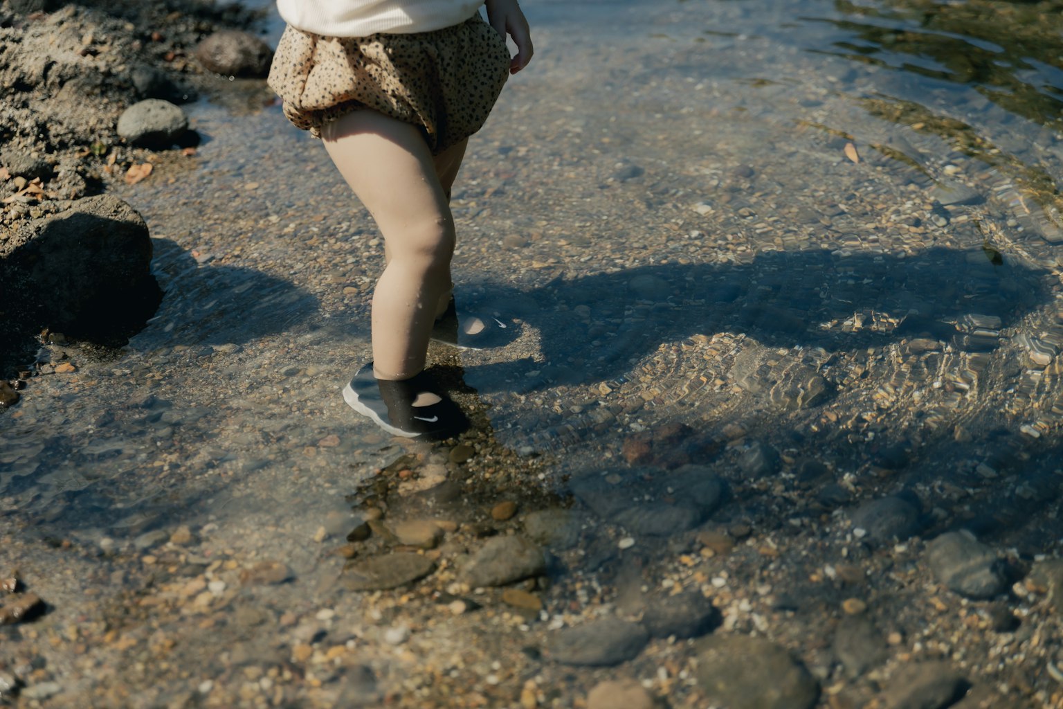 Child's feet wading in shallow water by the shore