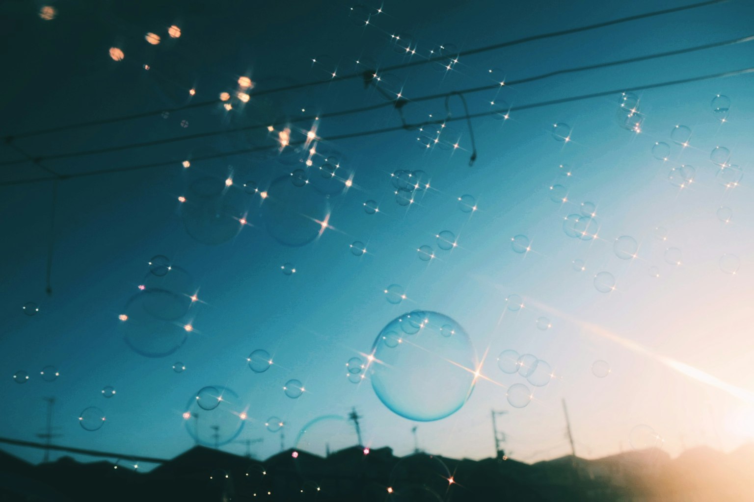 Burbujas flotando en un cielo azul con luz solar